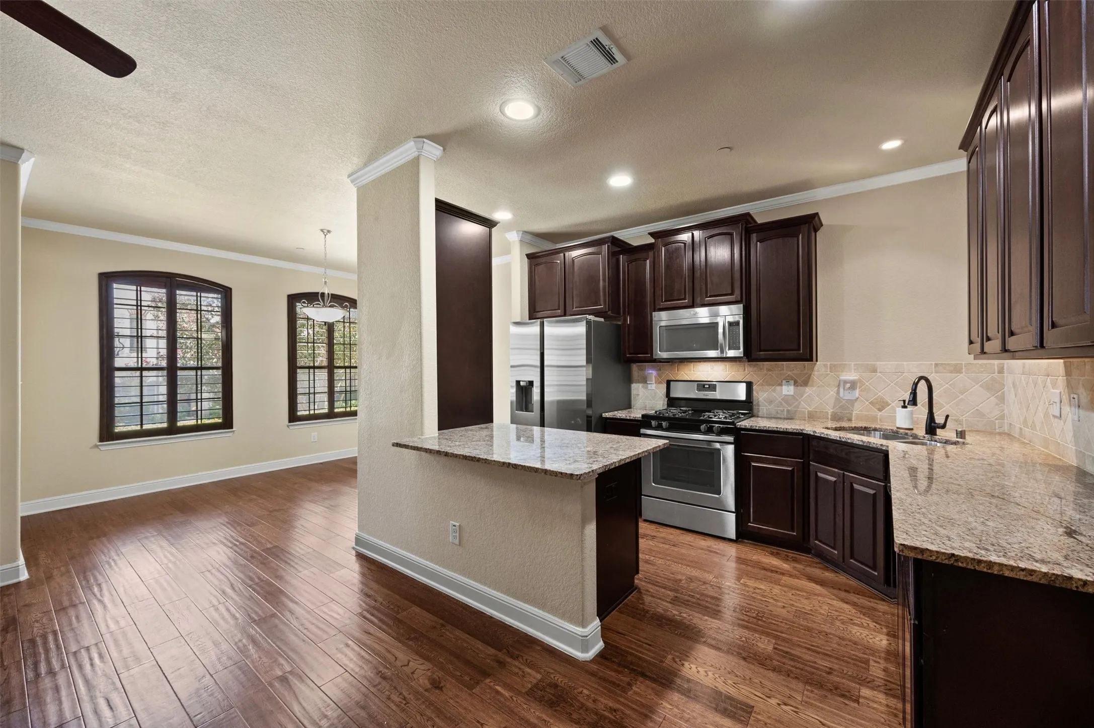 Kitchen featuring stainless steel appliances, dark wood-finish cabinetry, and light-toned countertops