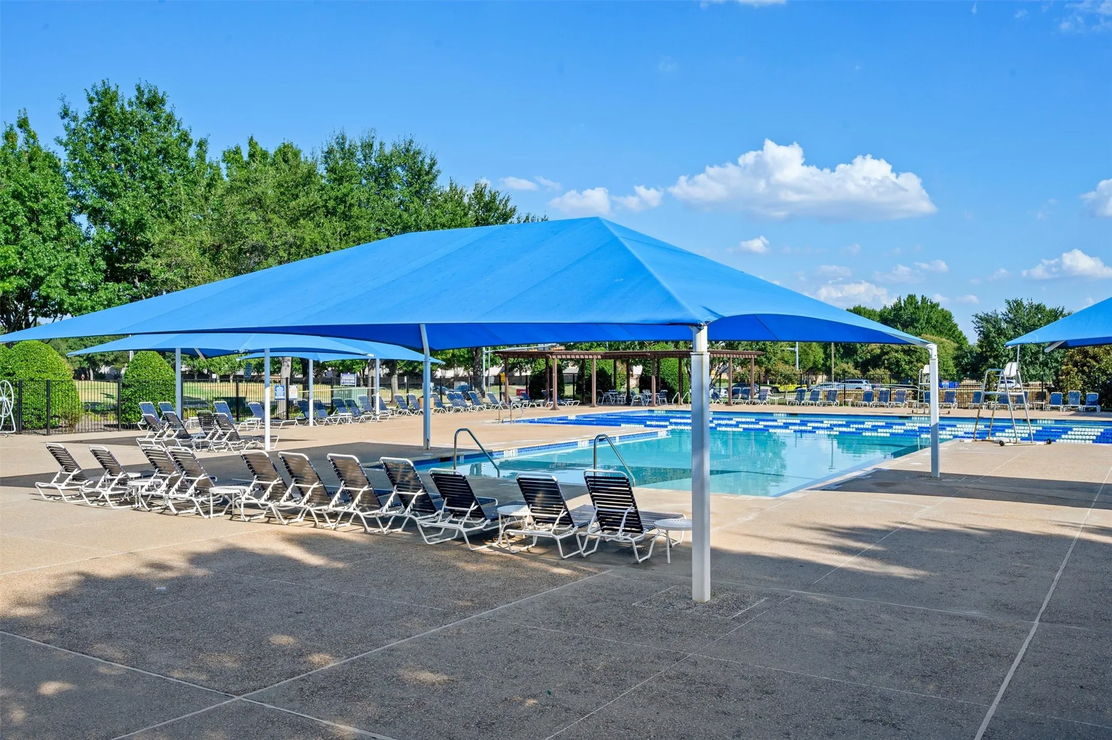 Expansive swimming pool with integrated lap lanes, shaded lounge areas, and surrounding concrete decking