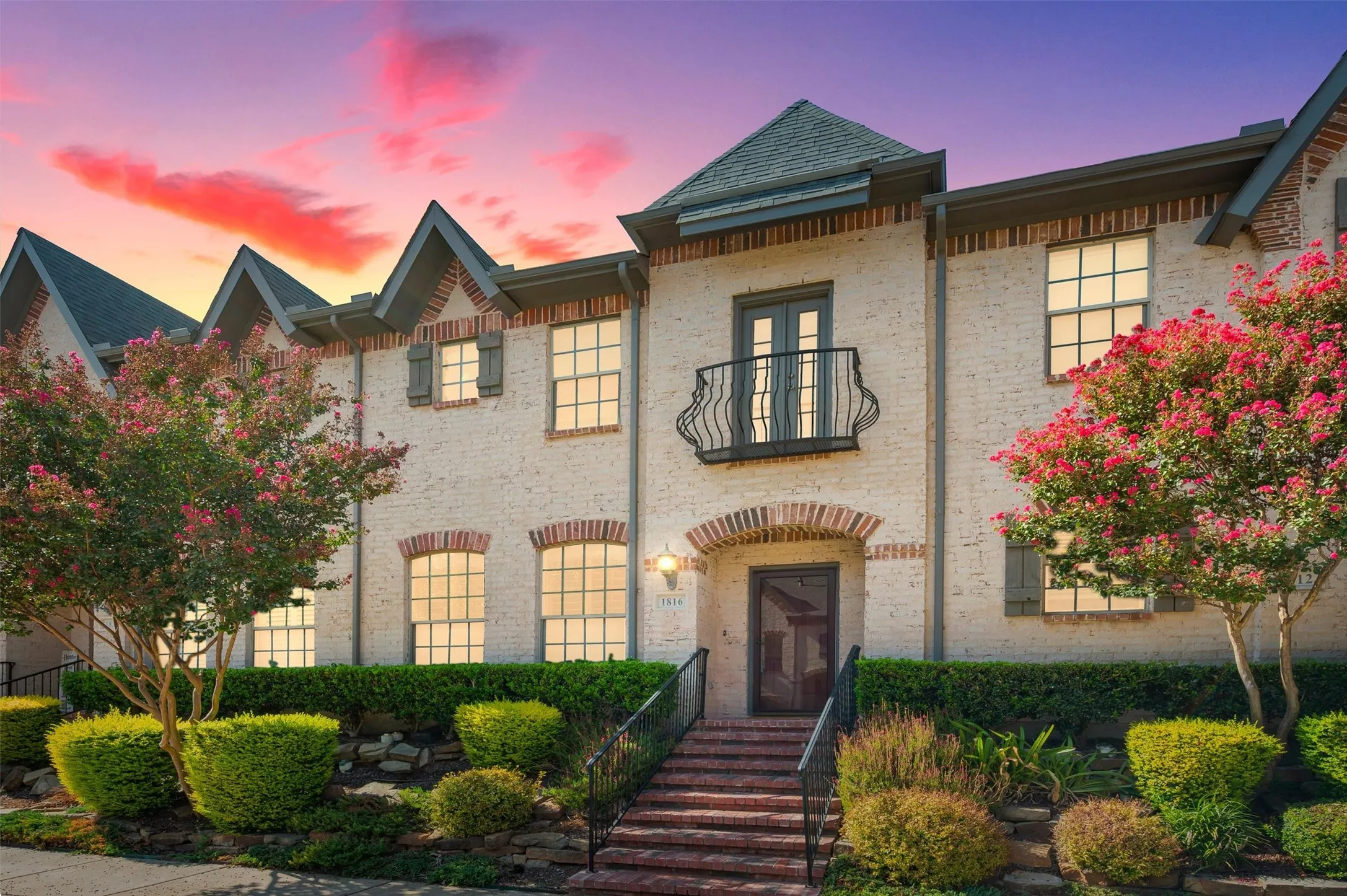 Beautiful white brick exterior accented by prominent architectural gables and a striking dark shingle roof, creating a timeless and sophisticated curb appeal.