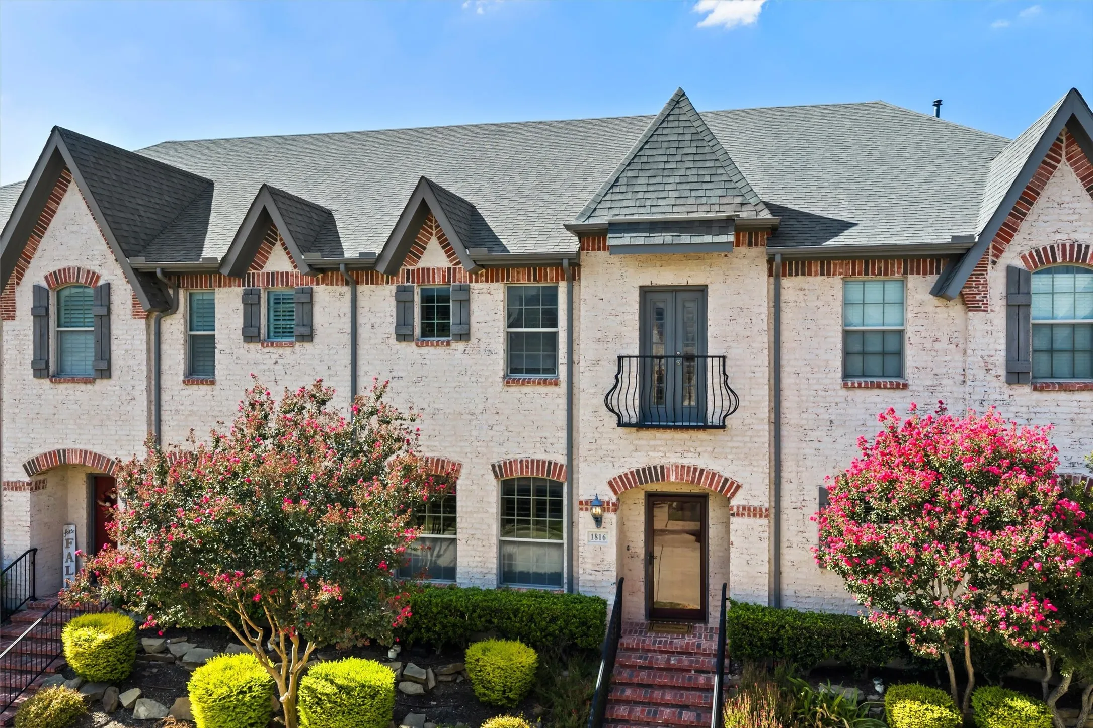Beautiful white brick exterior accented by prominent architectural gables and a striking dark shingle roof, creating a timeless and sophisticated curb appeal.