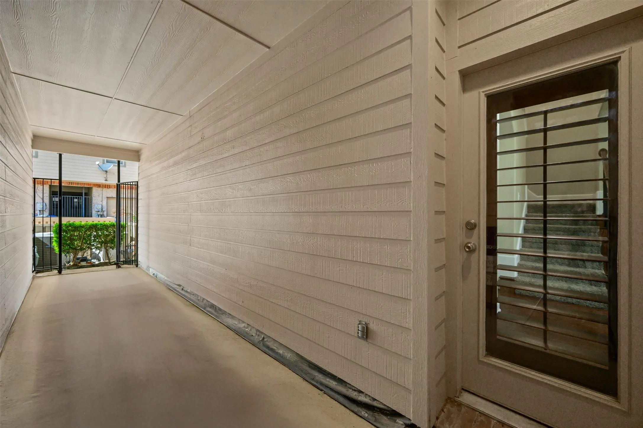Covered patio with a concrete surface, featuring horizontal siding and a frosted glass-paneled door