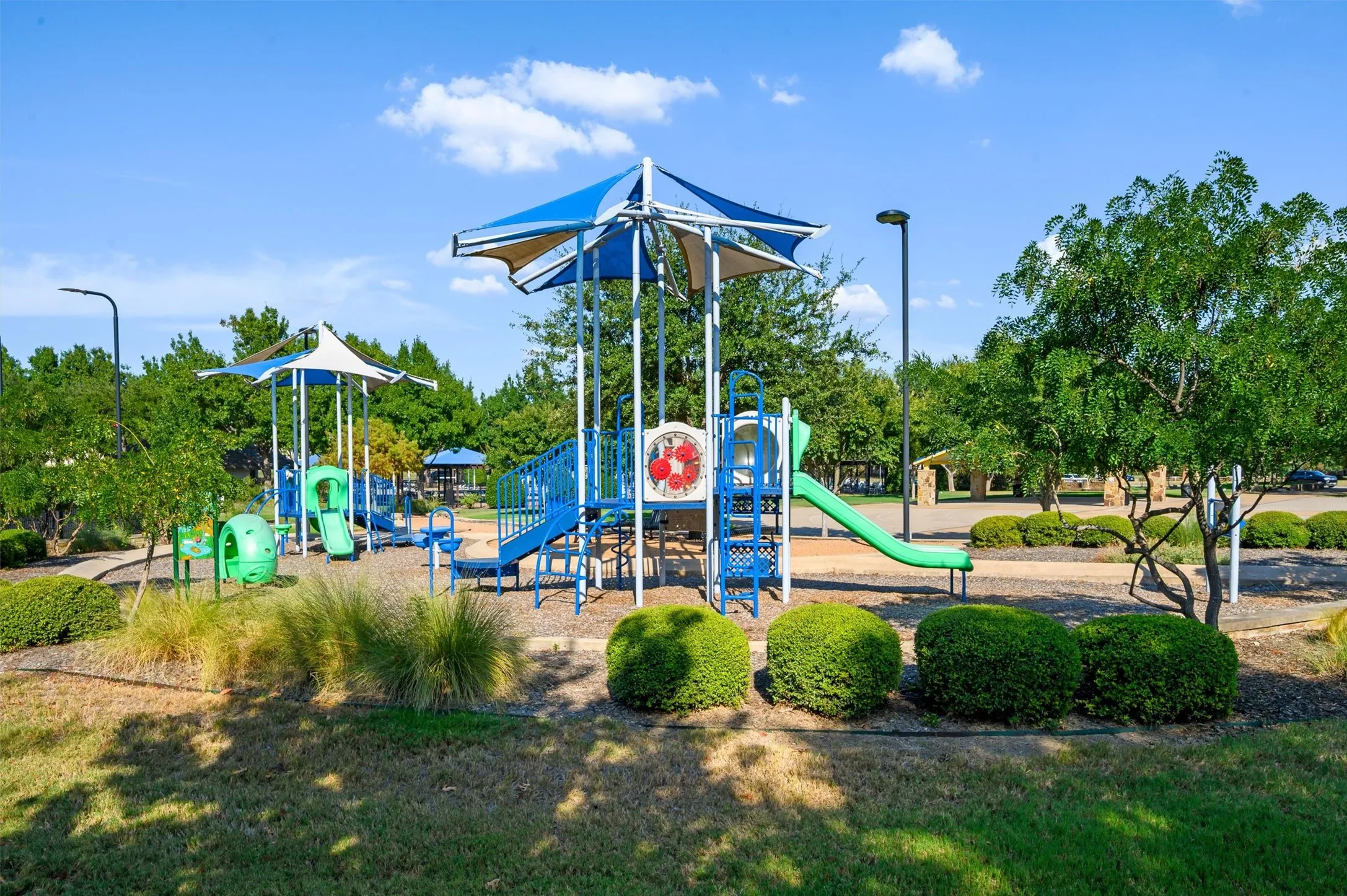 Community playground featuring multiple slides and shaded play structures