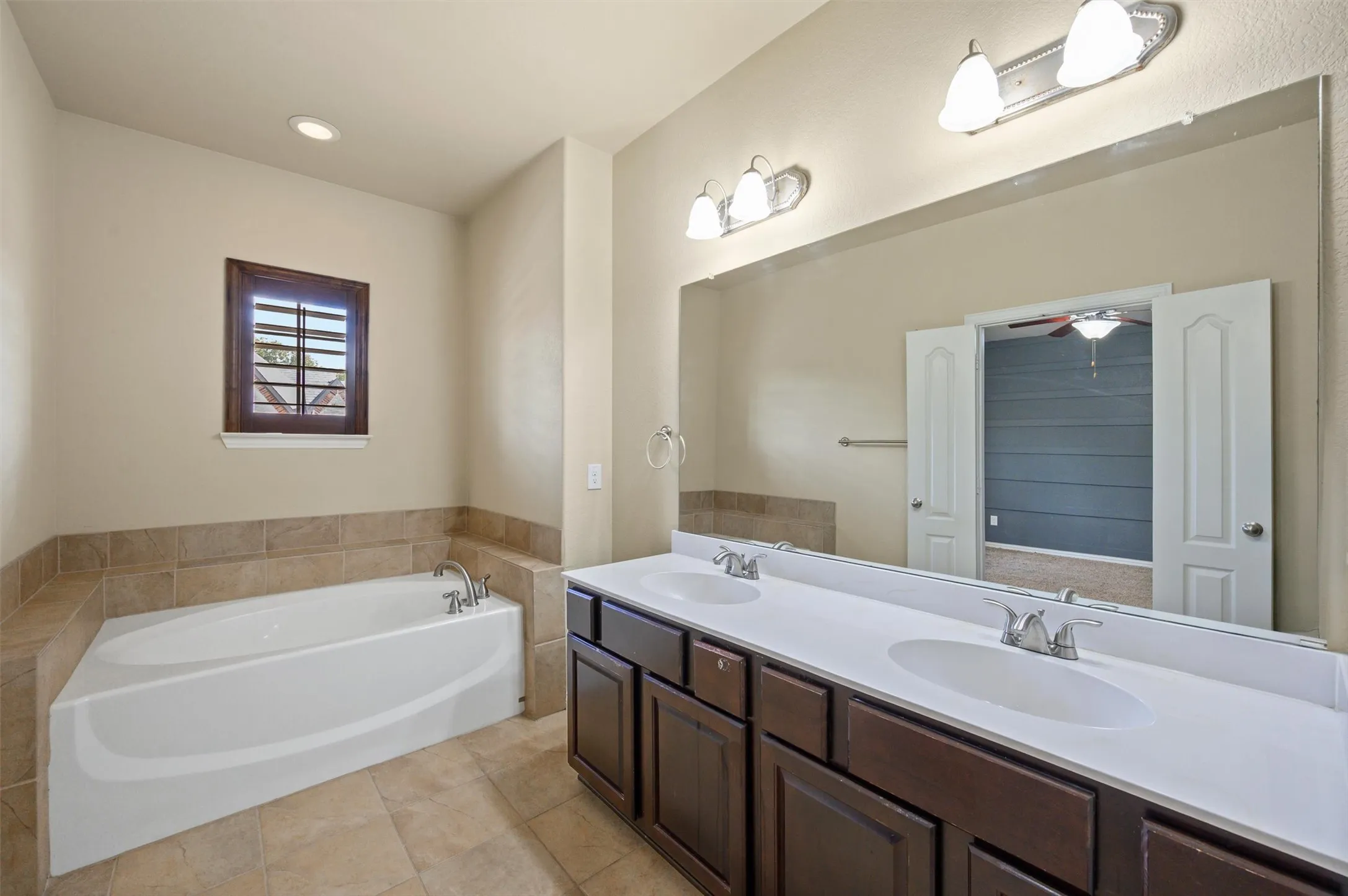 Dual vanity with integrated white sinks, dark wood-finish cabinetry, and a large wall-mounted mirror