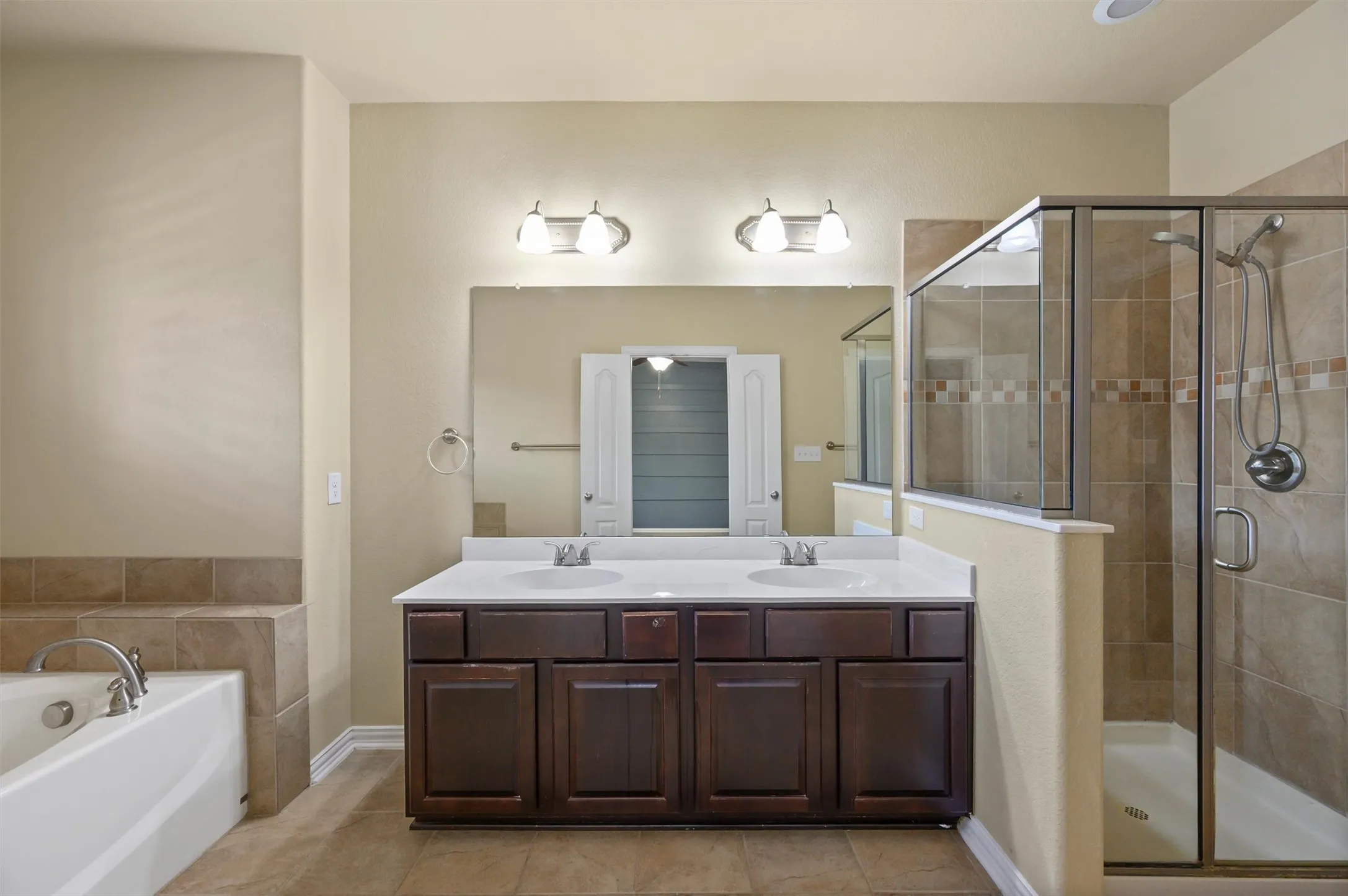 Dual vanity with undermount sinks, espresso-finish cabinetry, and a large wall mirror