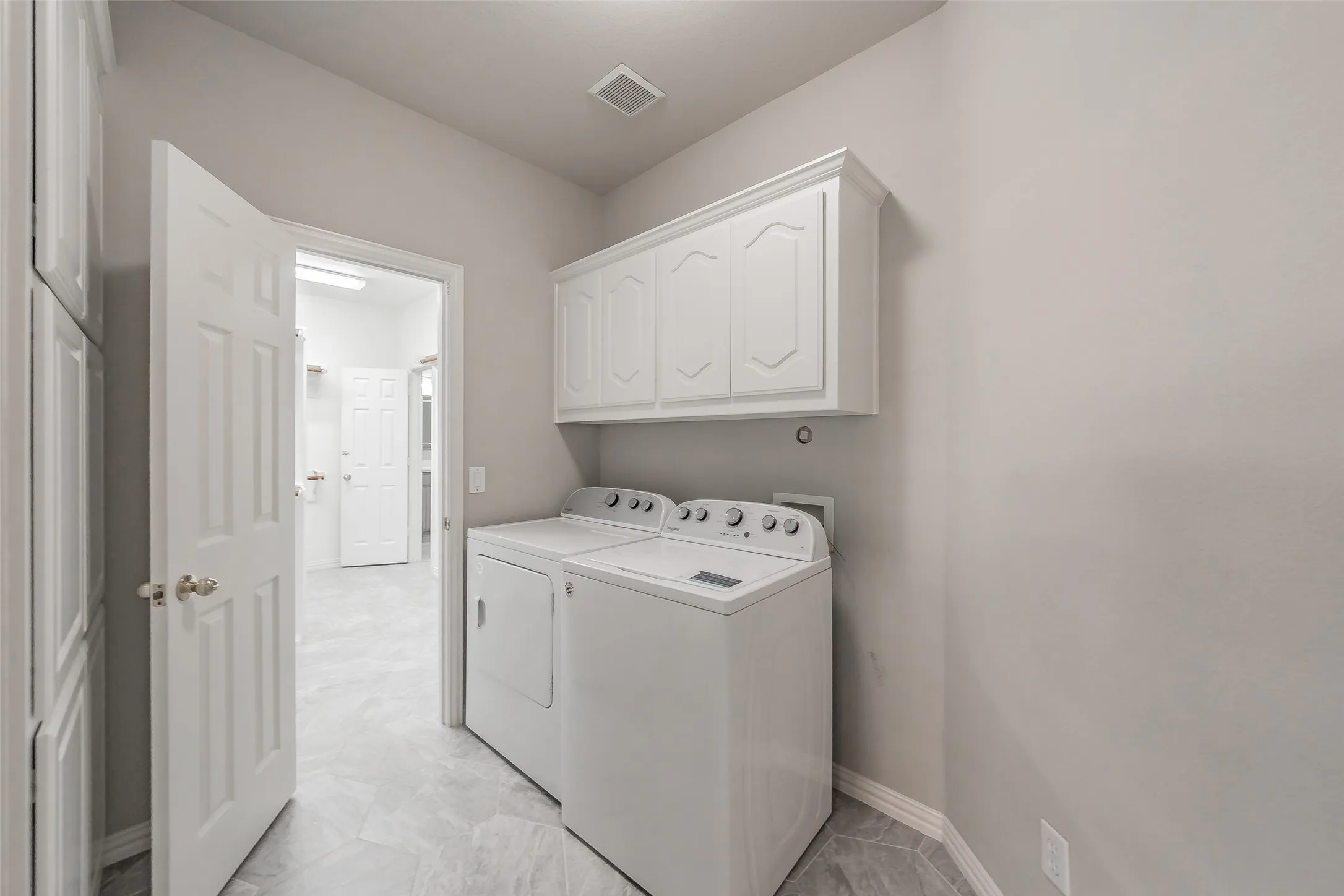 Laundry area featuring white cabinetry, grey tile flooring, and light-toned walls