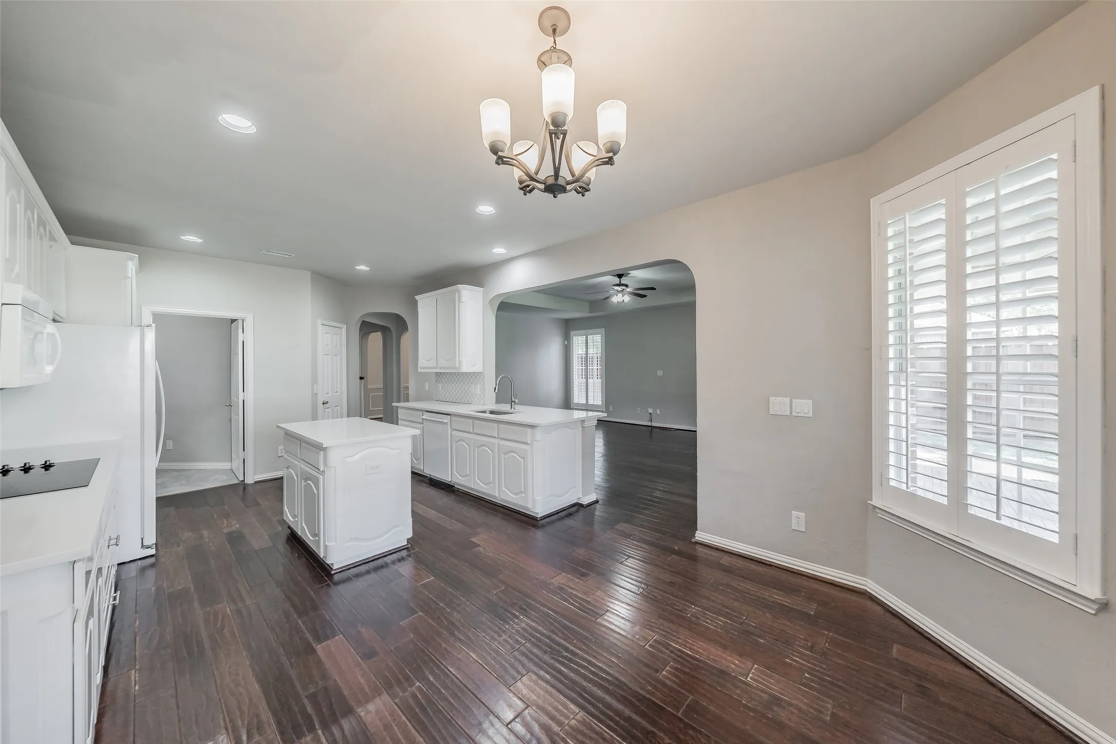Kitchen featuring dark wood-finish flooring, white cabinetry, a central island, and white countertops