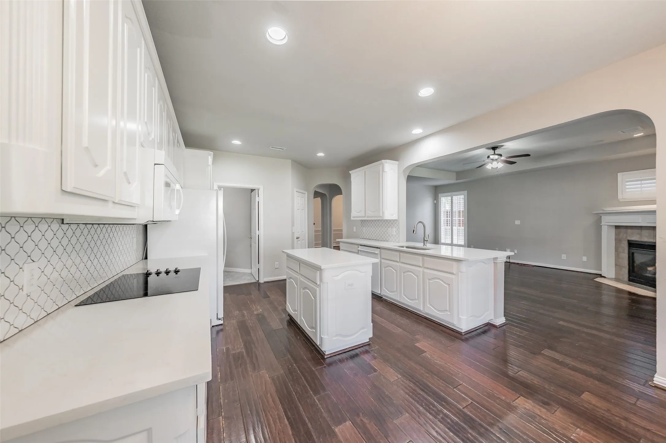 Kitchen with wood-finish flooring, white cabinetry, a built-in cooktop, and a kitchen island