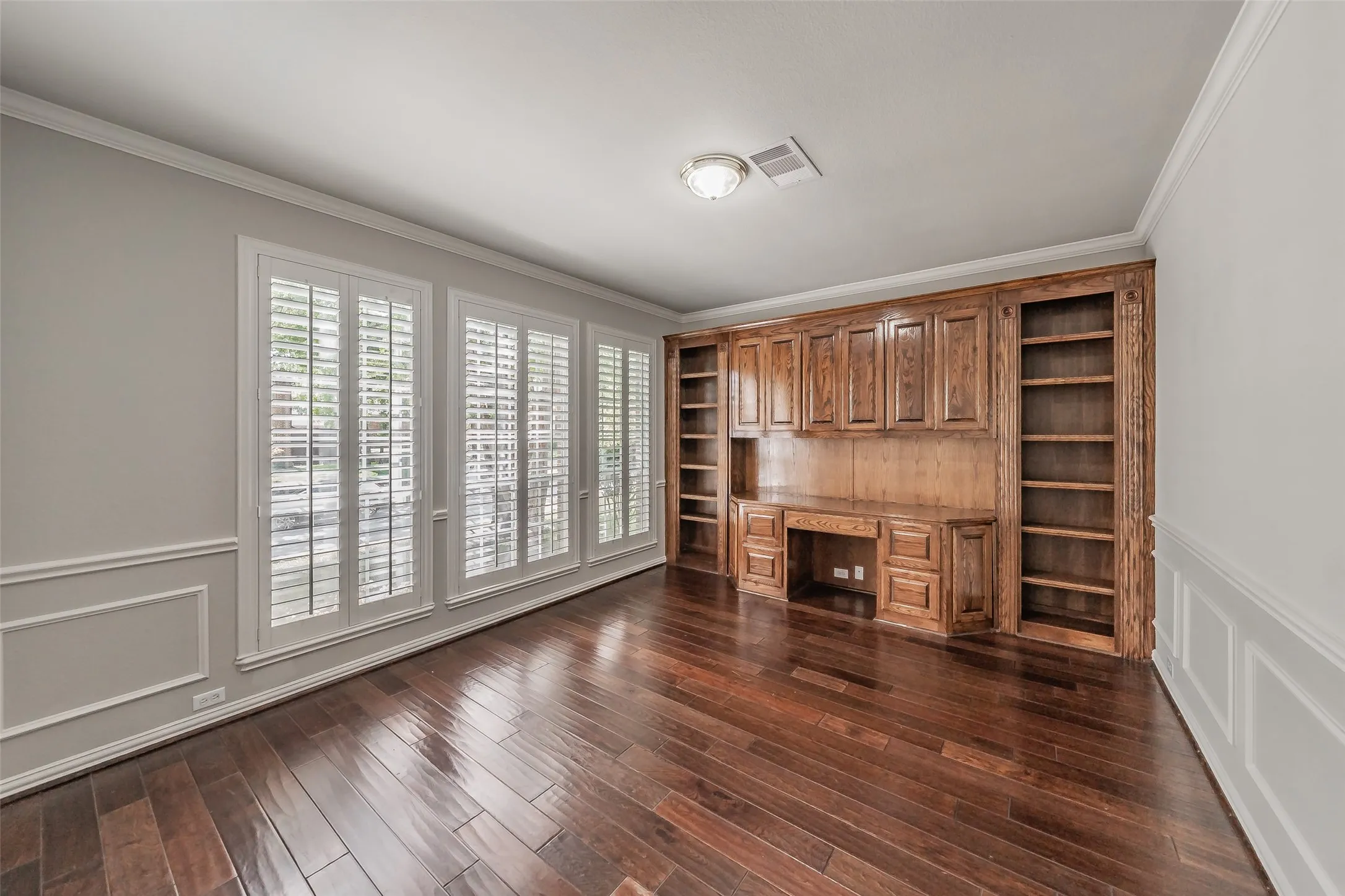 Hardwood-style flooring, custom built-in cabinetry, crown molding, wainscoting, and plantation shutters