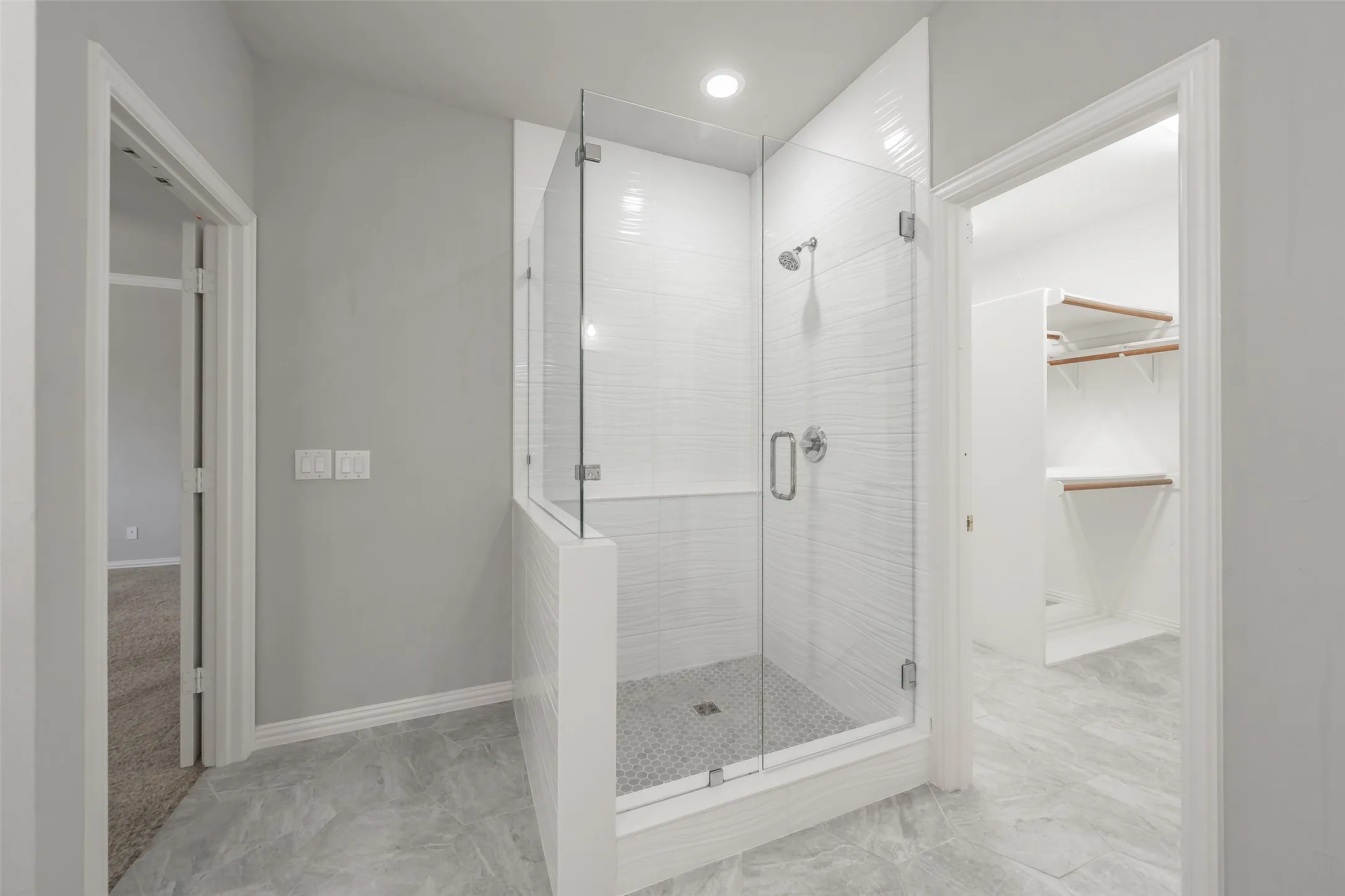 Walk-in shower with clear glass enclosure and subway tile surround