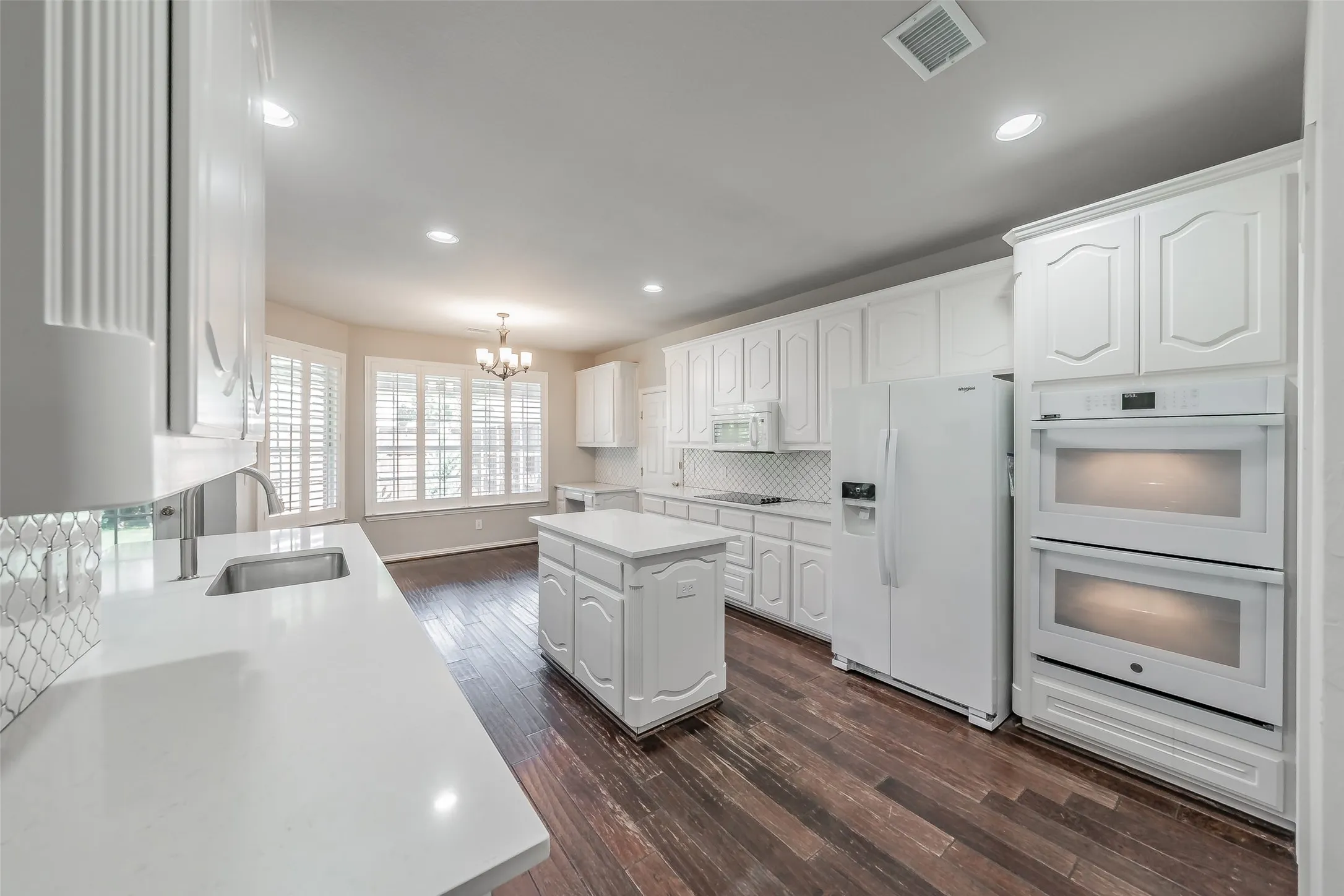 Kitchen featuring white cabinetry, a central island, recessed lighting, and wood-finish flooring