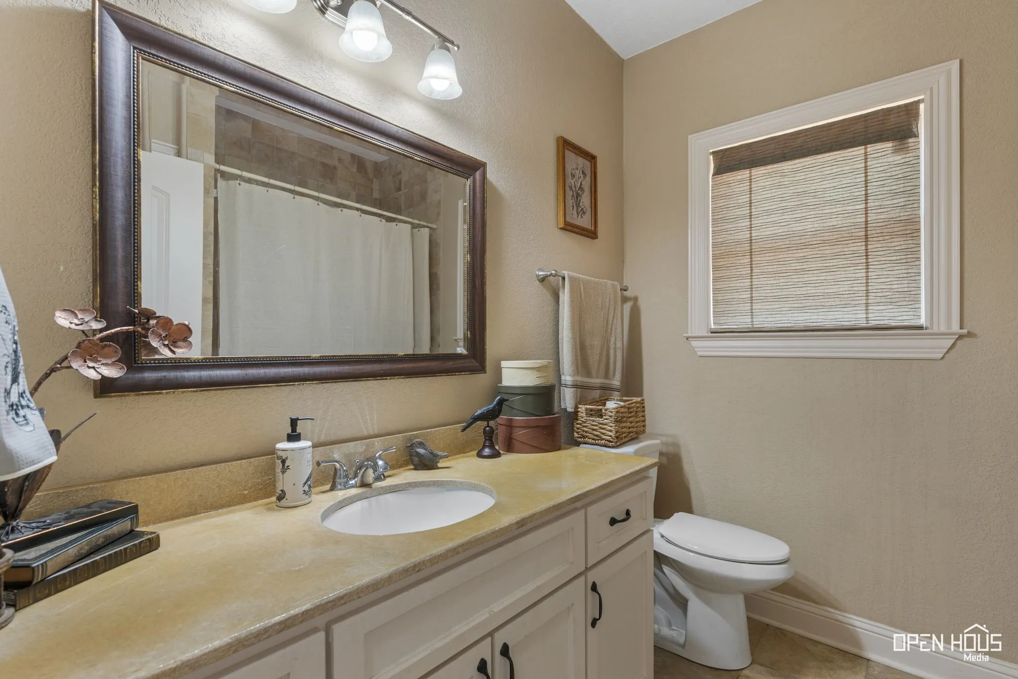 Vanity with an integrated sink, framed mirror, and a window with blinds