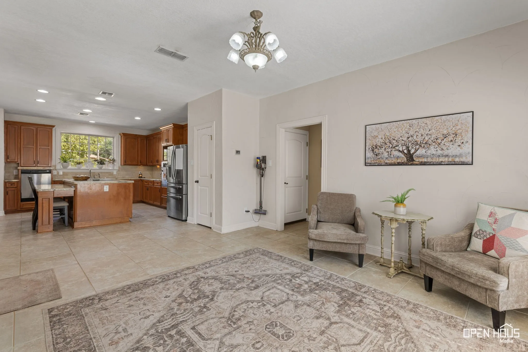 Spacious open-concept layout featuring tile flooring, a kitchen with wood cabinetry, and stainless steel appliances