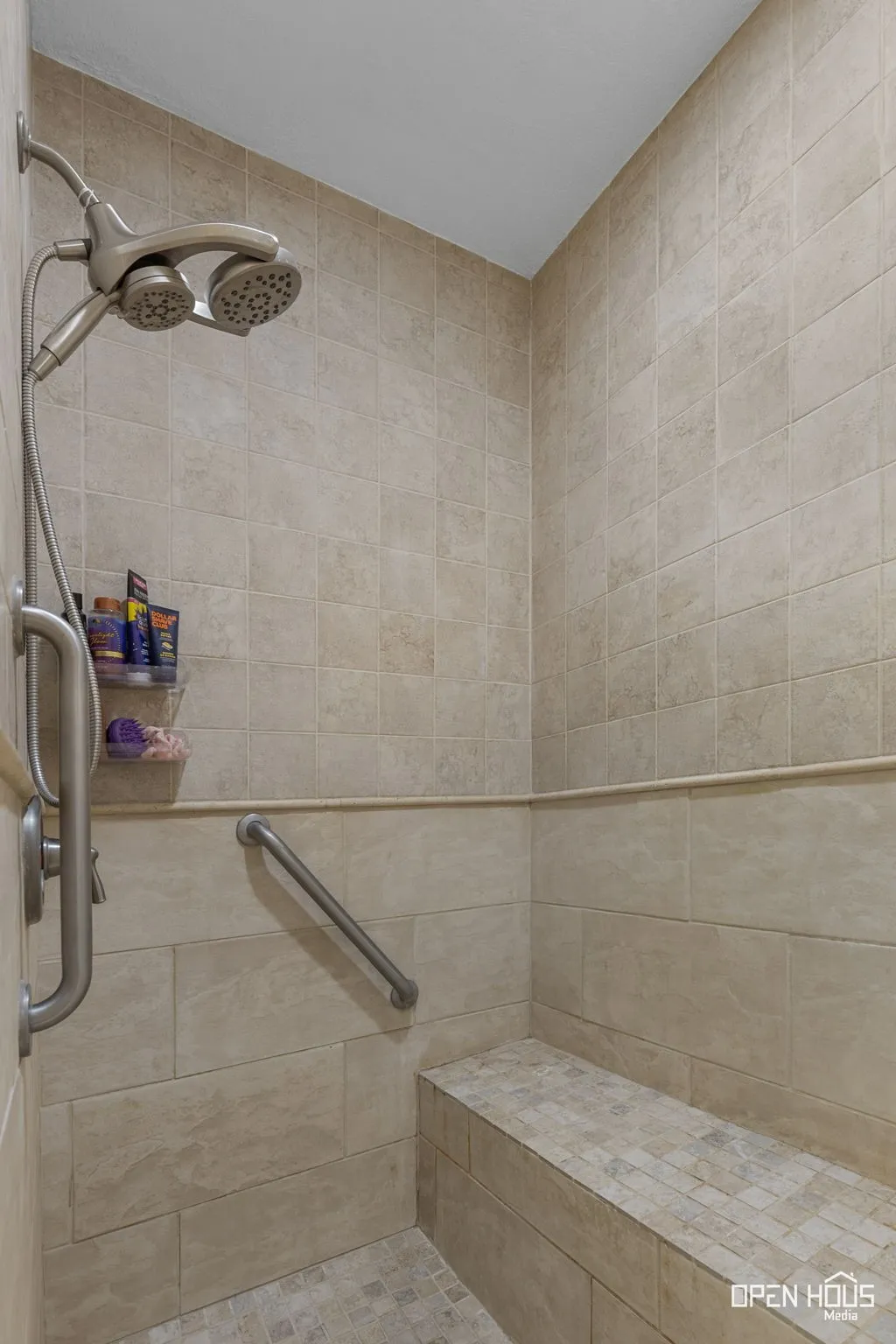 Tiled shower stall with a built-in bench, dual shower heads, and an integrated grab bar