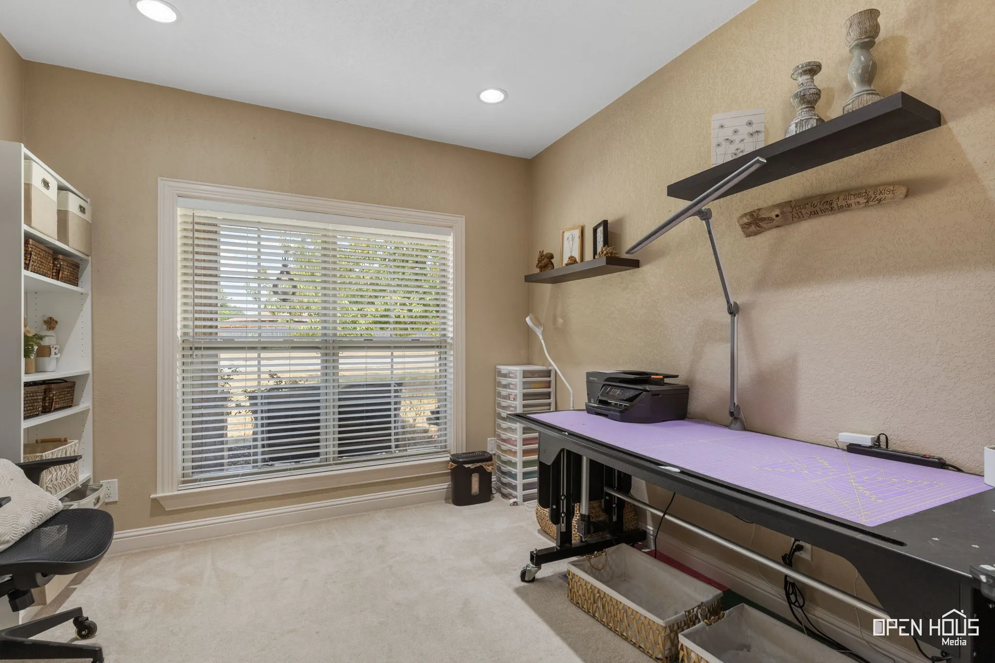 Recessed lighting, wall-mounted shelving, large window with blinds, and light-colored carpeting