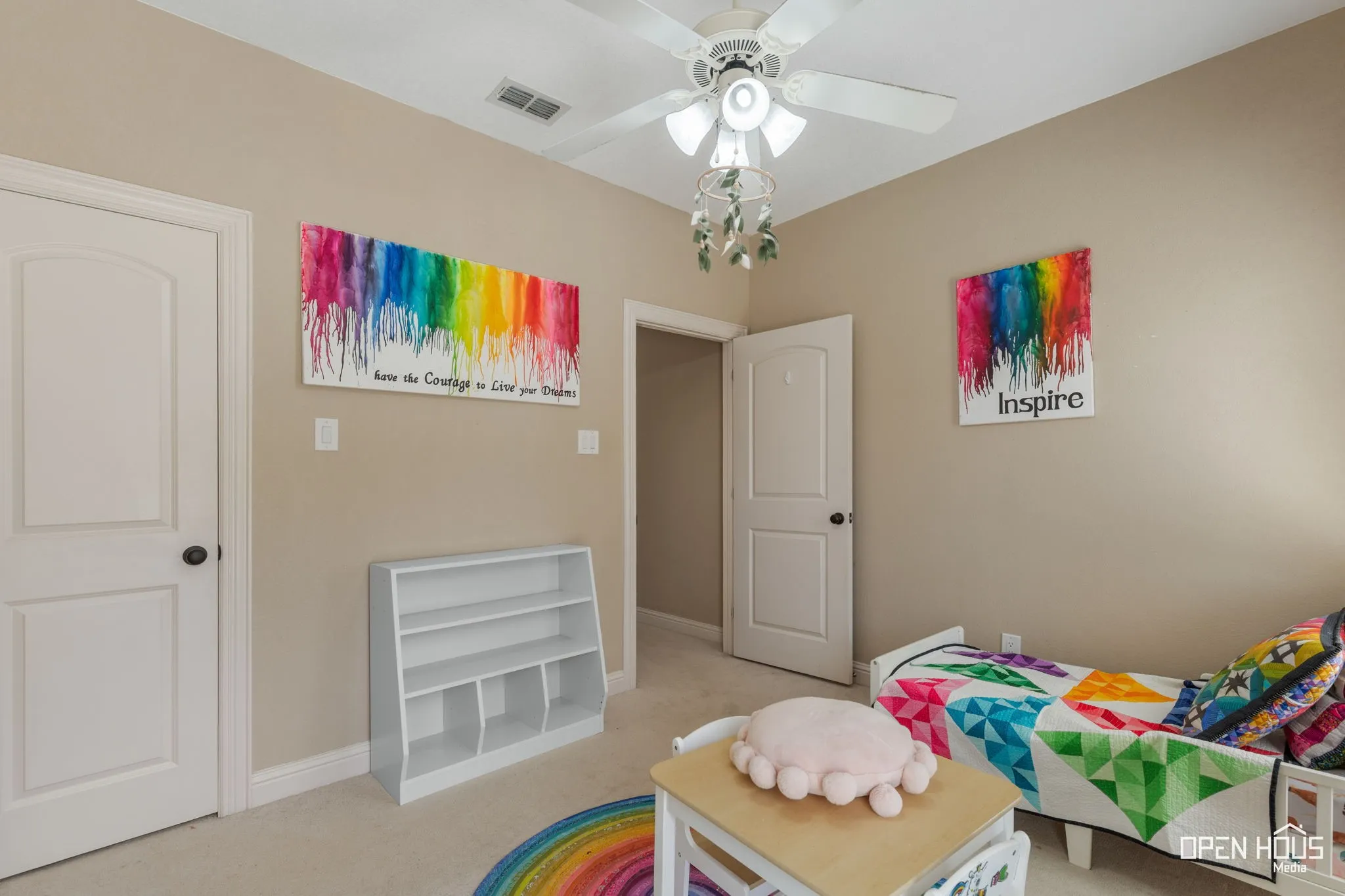 Bright, neutral-toned bedroom featuring ceiling fan with integrated lighting, white six-panel doors, and neutral carpet flooring