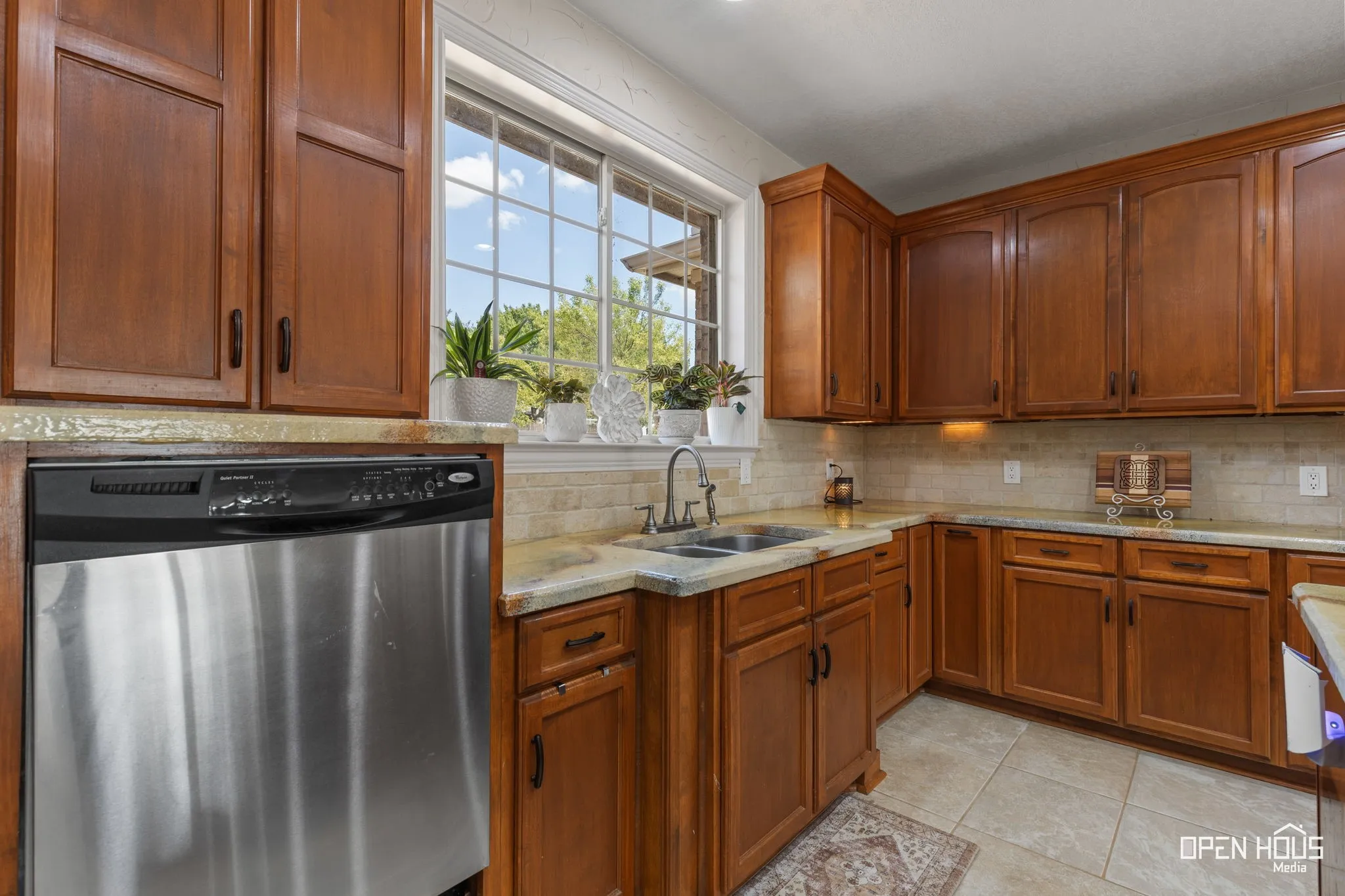 Kitchen featuring shaker-style wood cabinetry, light-toned countertops, and a stainless steel dishwasher