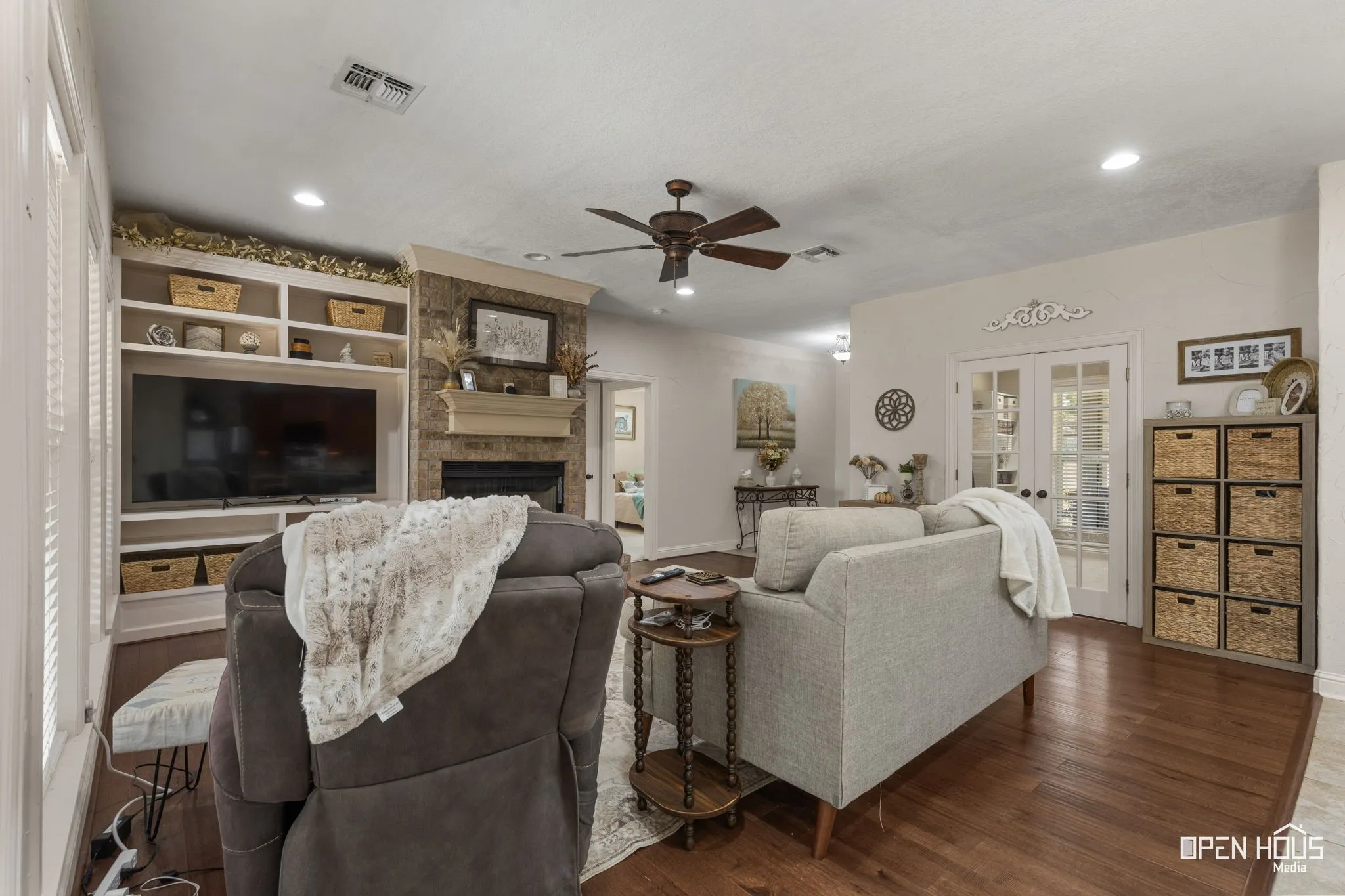 Recessed lighting, wood-finish flooring, ceiling fan, built-in media center, and a stone-clad fireplace with a mantel