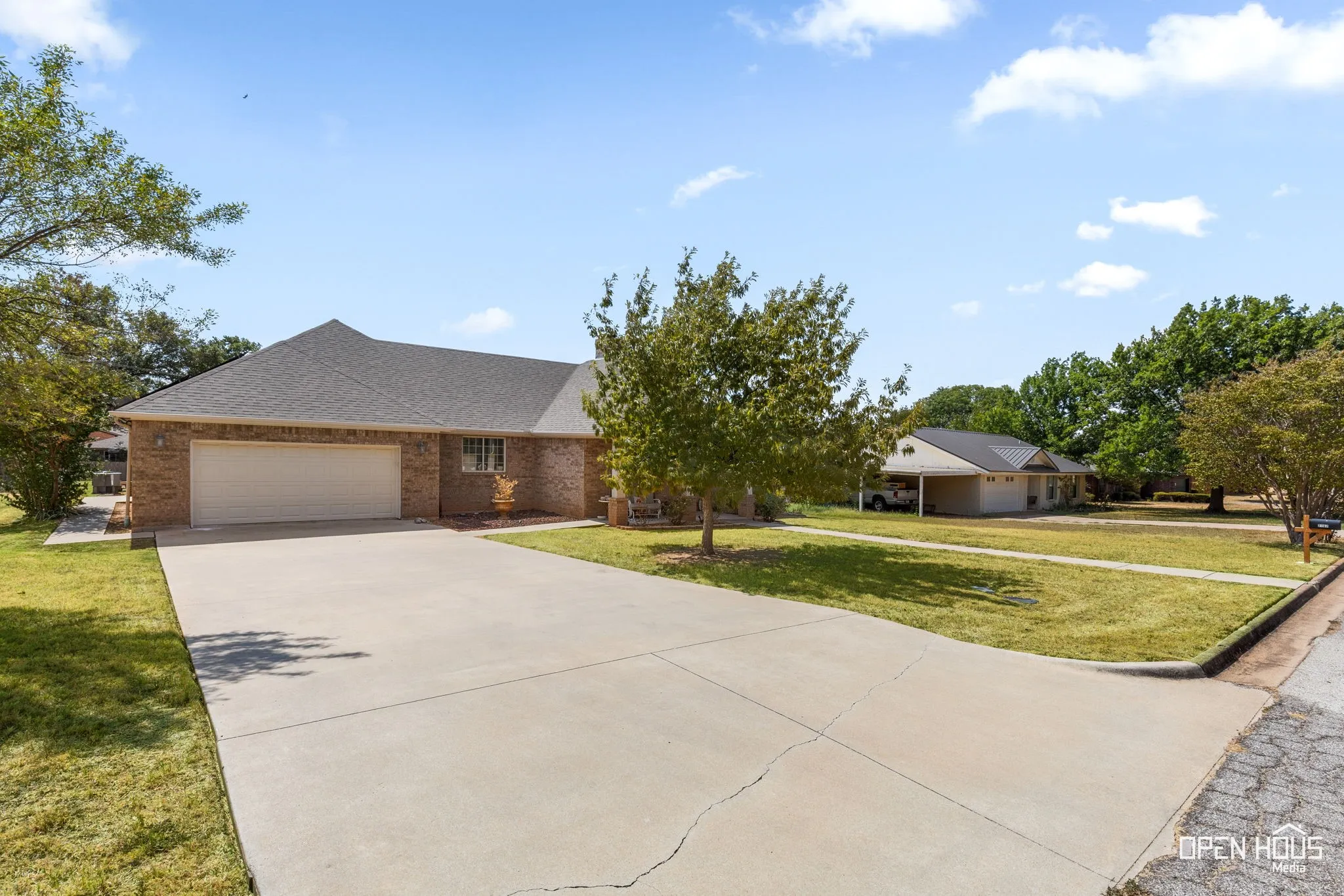 Brick exterior residence with an attached garage, concrete driveway, and a shingle roof