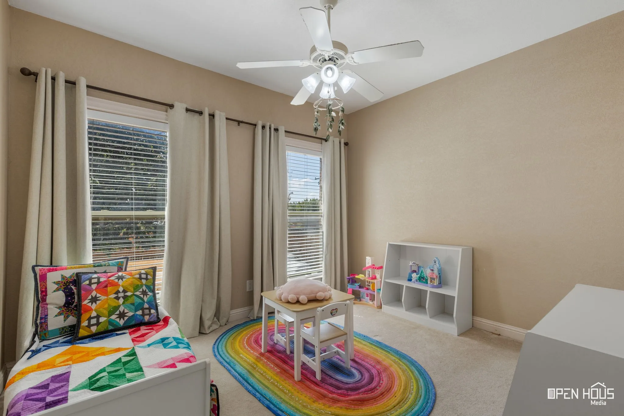 Two windows with blinds and curtains, ceiling fan with light fixture, neutral wall color, and carpeted flooring