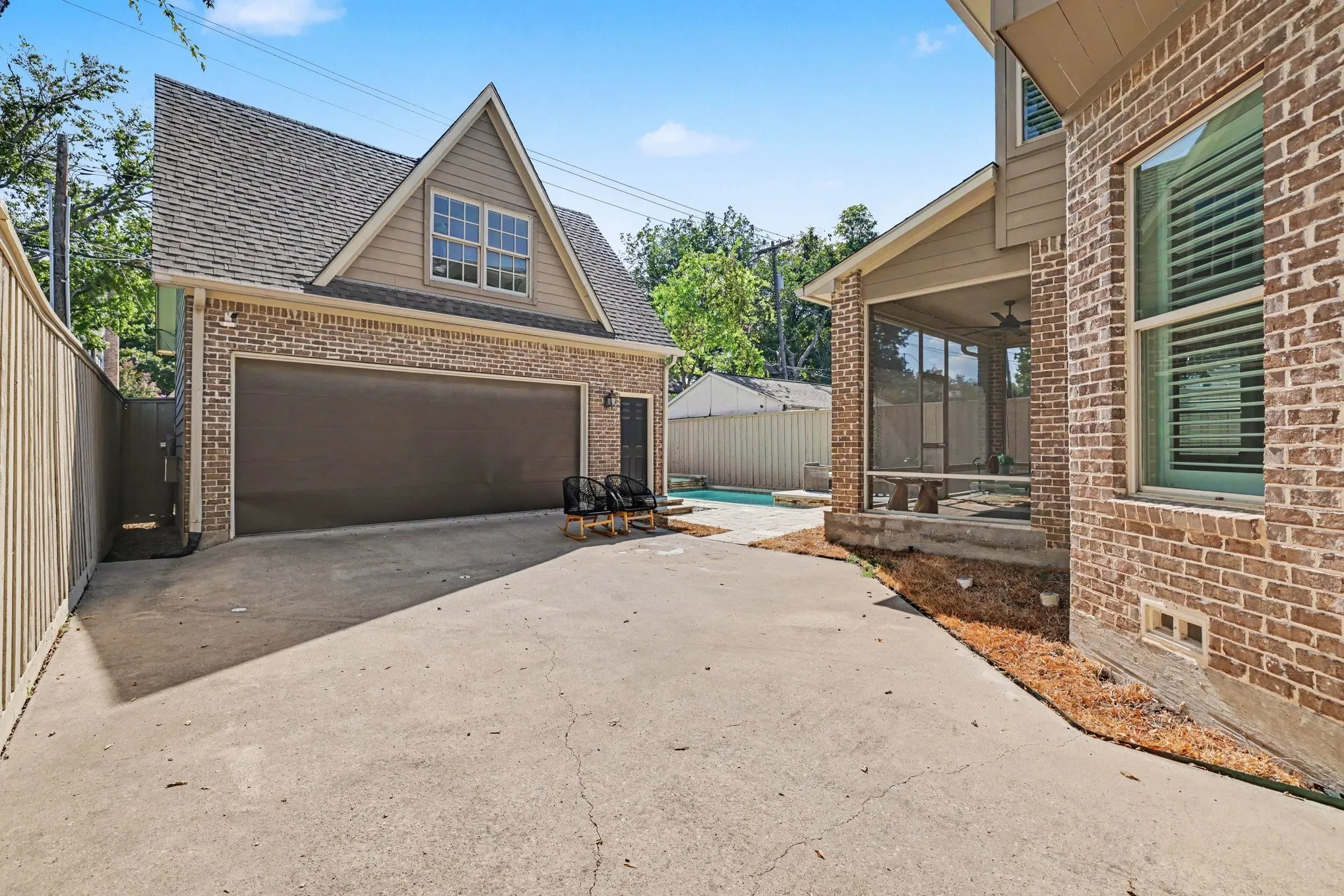 Detached brick garage with an overhead door, wood siding, and an attic window
