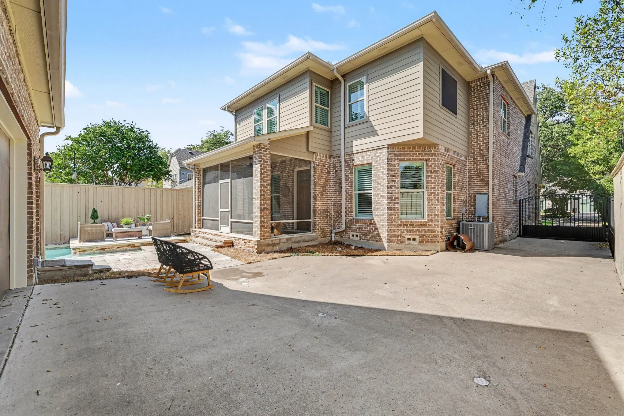 Two-story brick and siding exterior with a screened porch and private entry gate