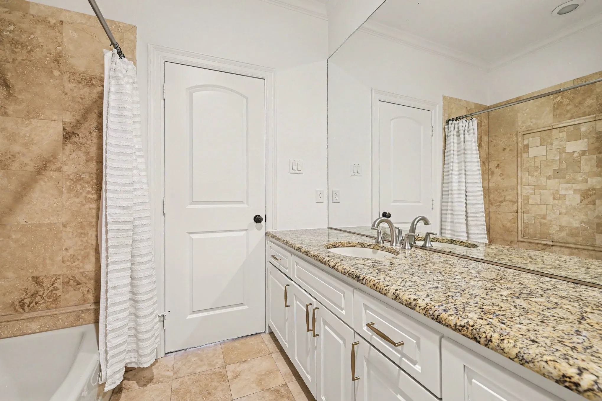Bathroom featuring a white vanity with a granite countertop, dual undermount sinks, and polished chrome faucets