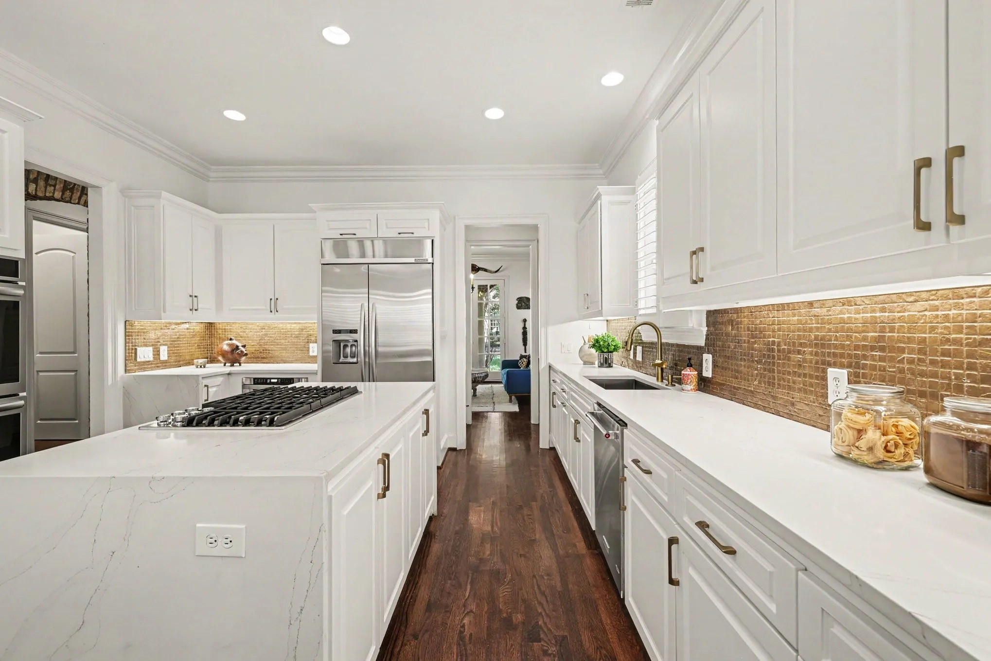 Gourmet kitchen with white cabinetry, stainless steel appliances, a center island featuring a gas cooktop, and gold-toned tile backsplash