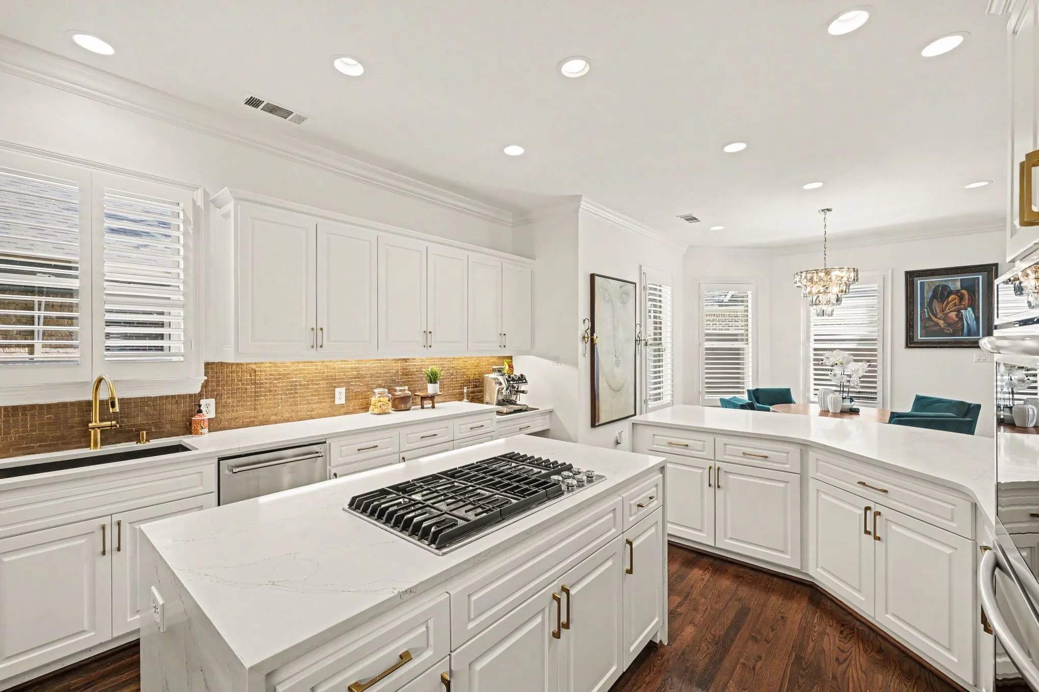 Kitchen featuring white shaker-style cabinetry, a built-in gas range, stainless steel appliances, and a curved island with countertop seating
