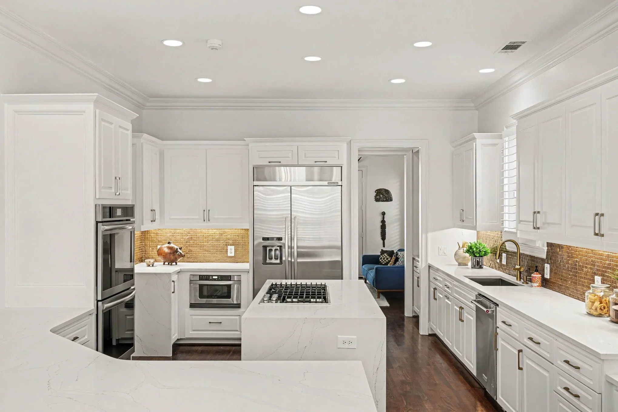 Gourmet kitchen with white cabinetry, stainless steel appliances, white countertops, a central island with a gas cooktop, and hardwood flooring
