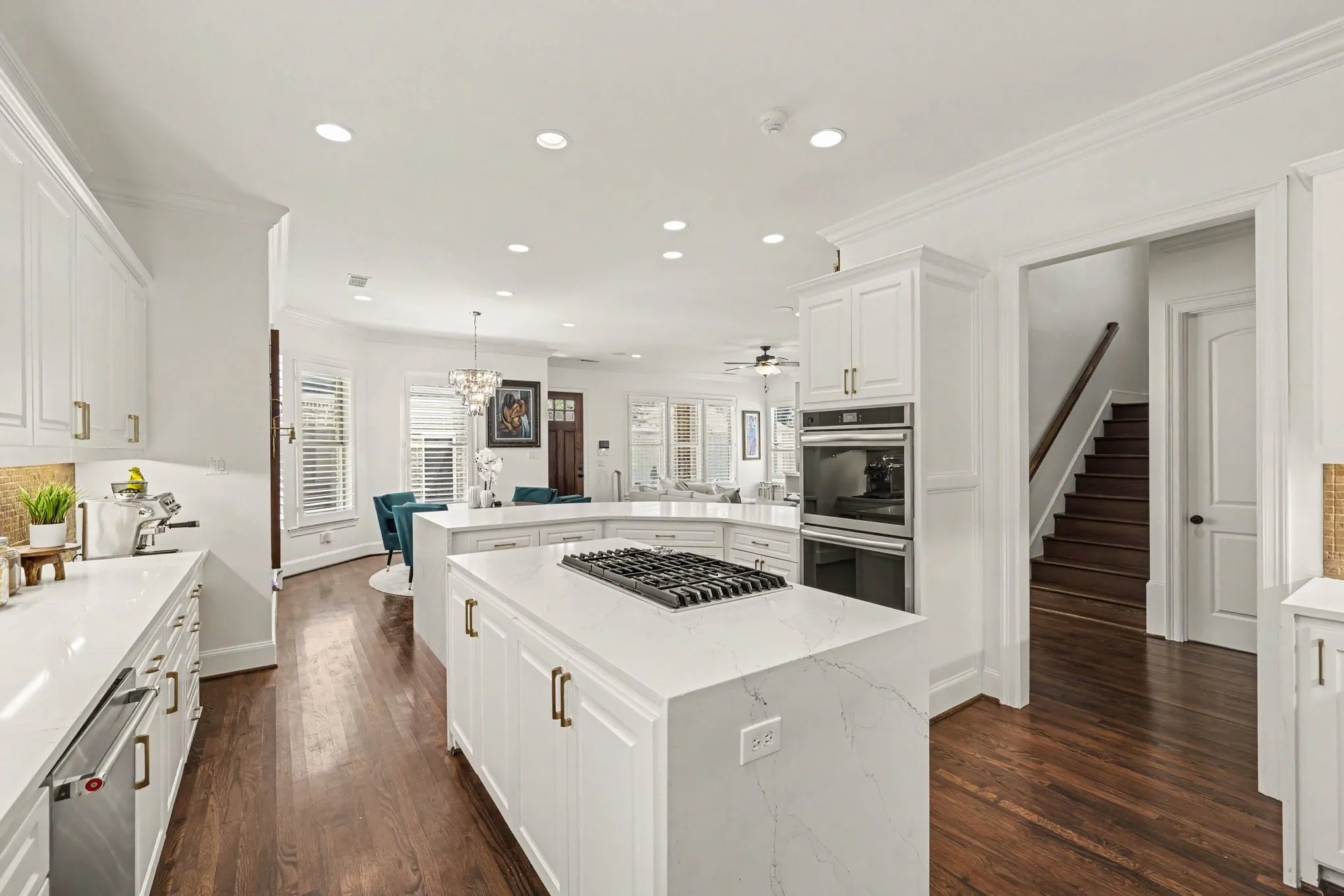 Gourmet kitchen featuring white cabinetry, integrated stainless steel appliances, and a gas cooktop on a center island
