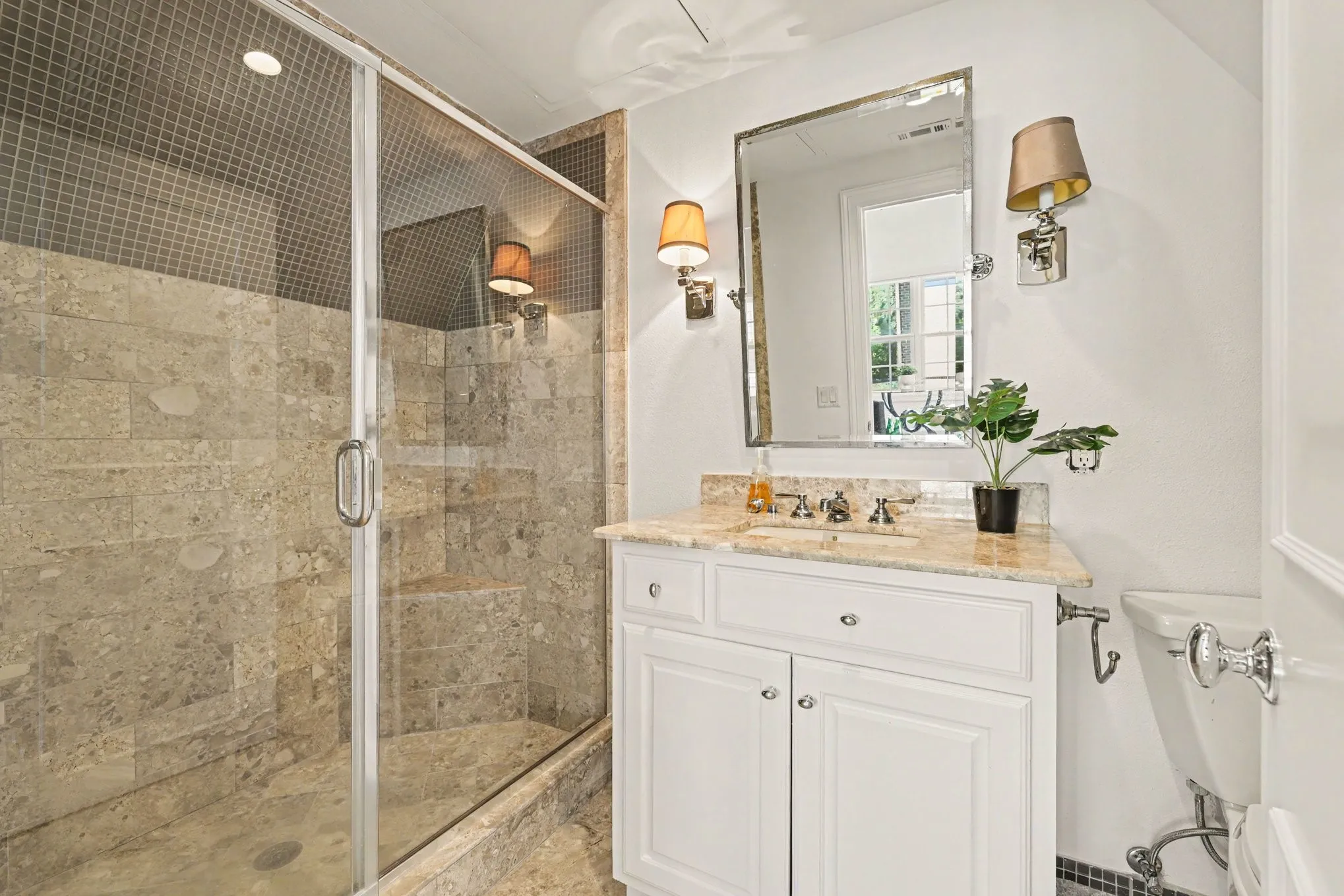 Glass-enclosed shower with natural stone tile, an integrated shower bench, and a mosaic tile accent