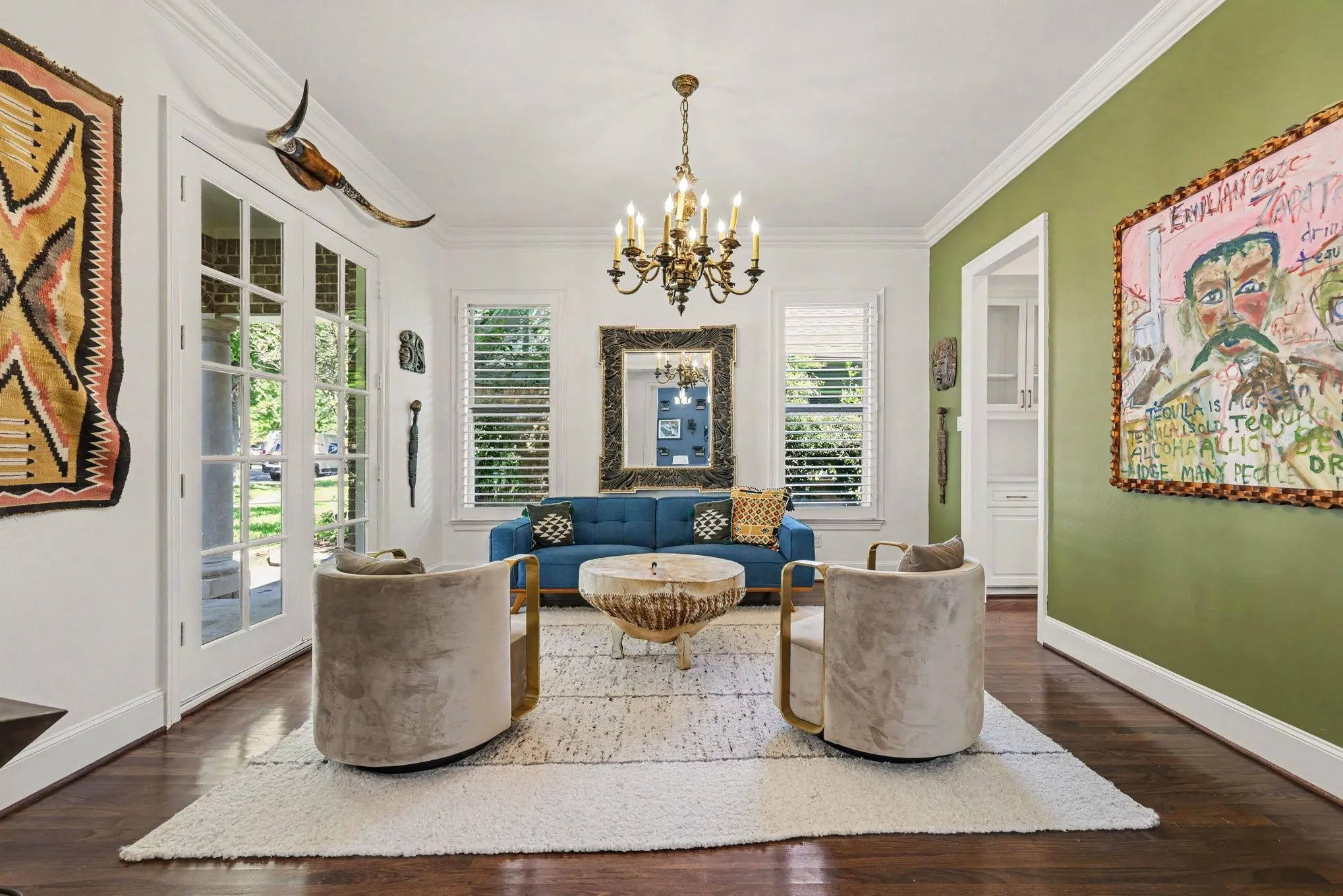 Hardwood flooring, elegant crown molding, a brass chandelier, and white French doors with transom windows