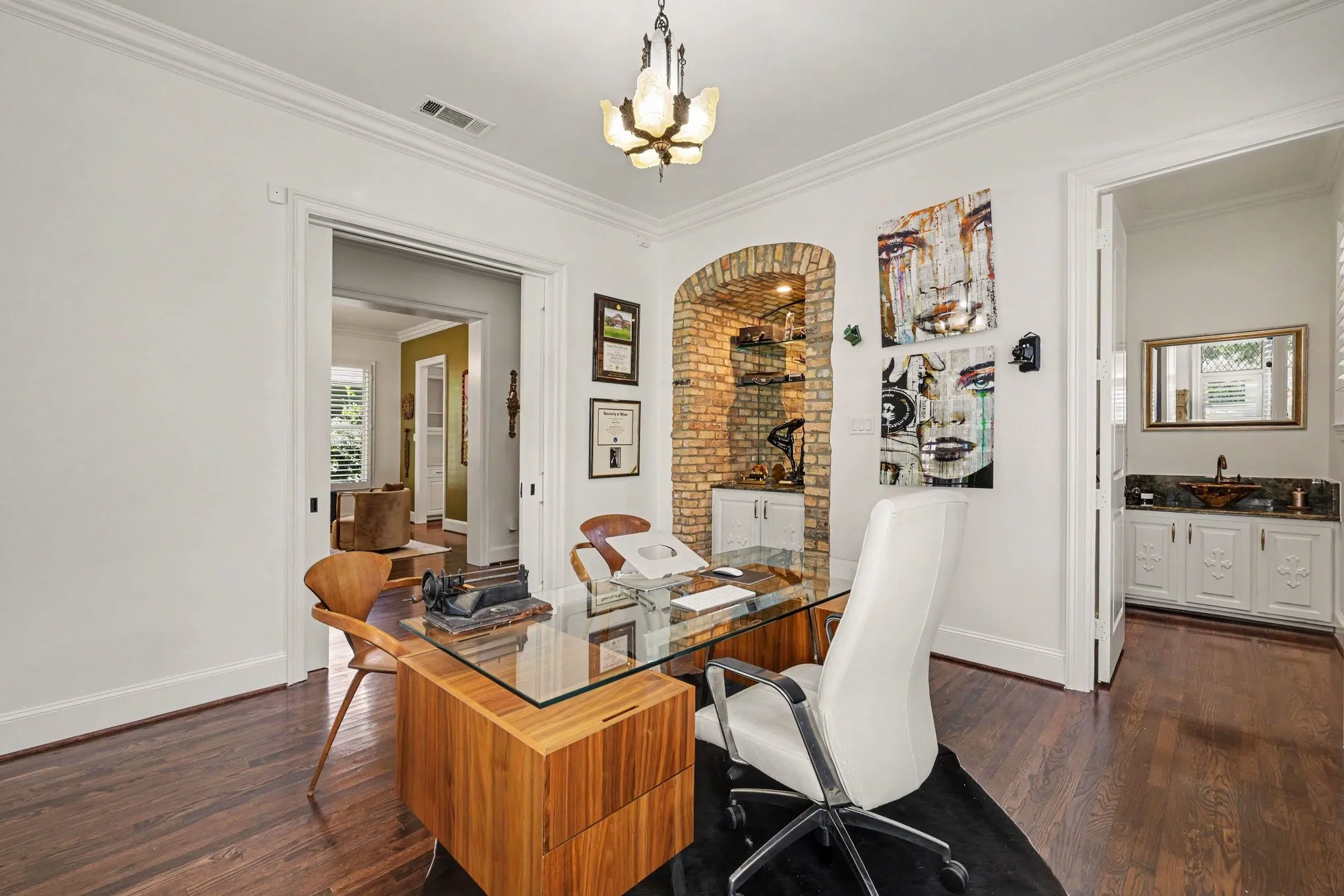 Hardwood flooring, crown molding, built-in brick alcove with shelving, built-in cabinetry, and integrated lighting