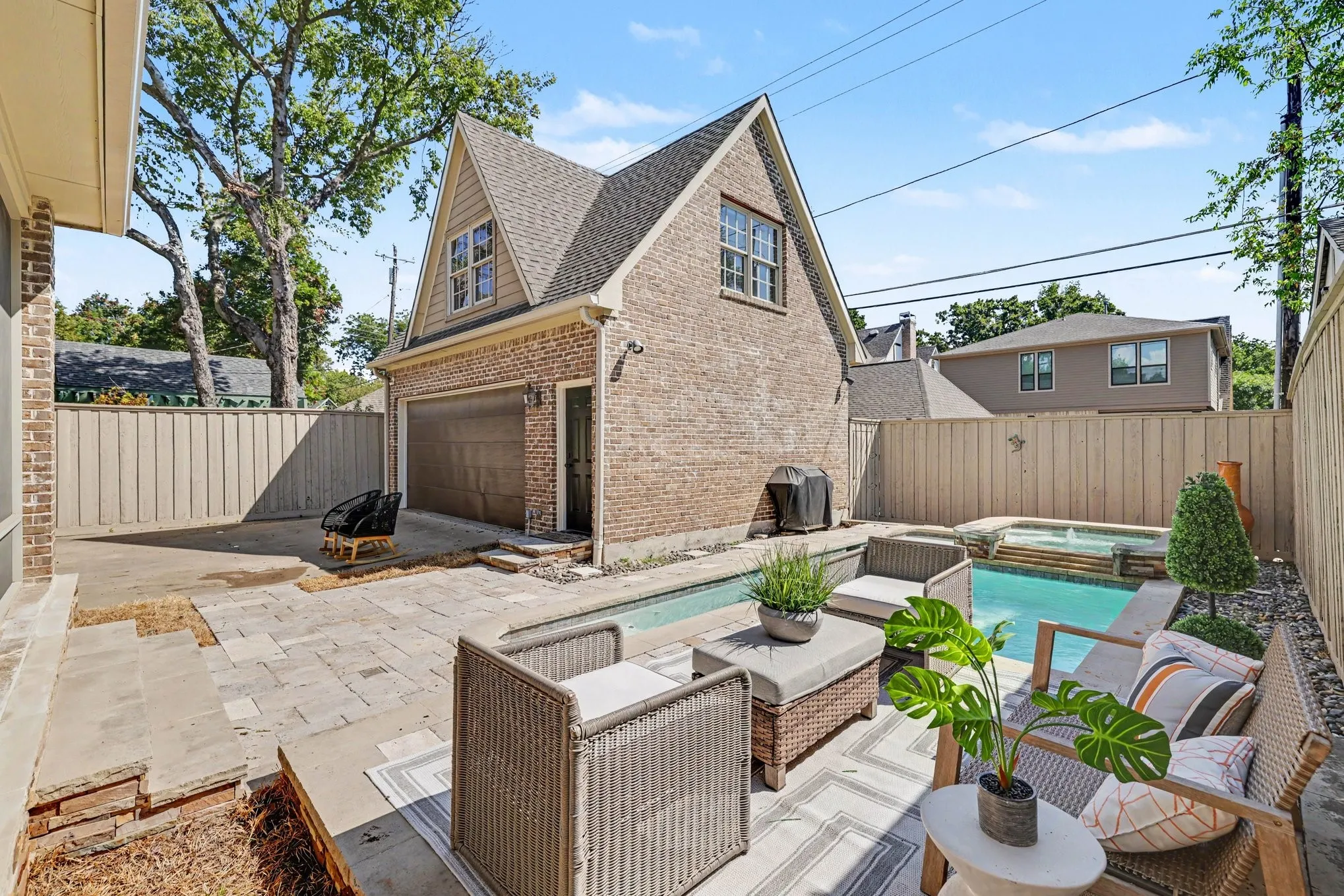 Brick-clad detached garage with an upper dormer window, a built-in swimming pool, and a jetted spa