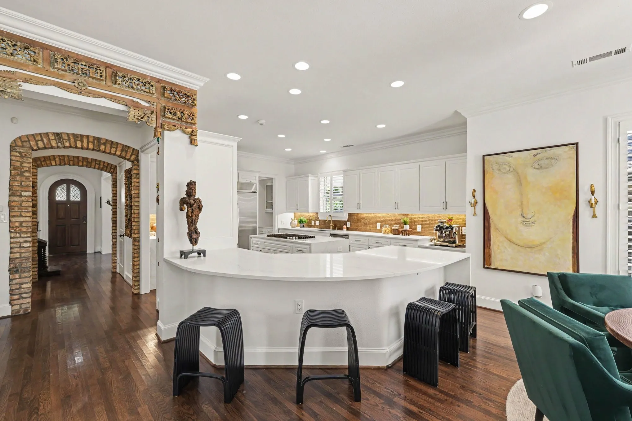 Expansive kitchen with a curved island, white cabinetry, integrated stainless steel appliances, and wood-finish flooring