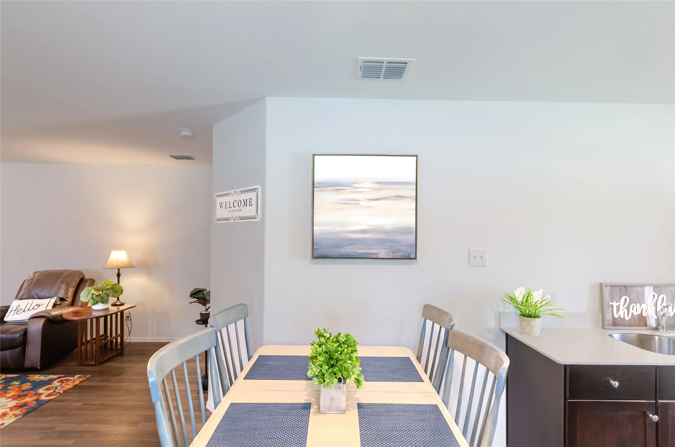 Open-concept design featuring wood-finish flooring, a dining area, and a kitchen counter with an integrated sink