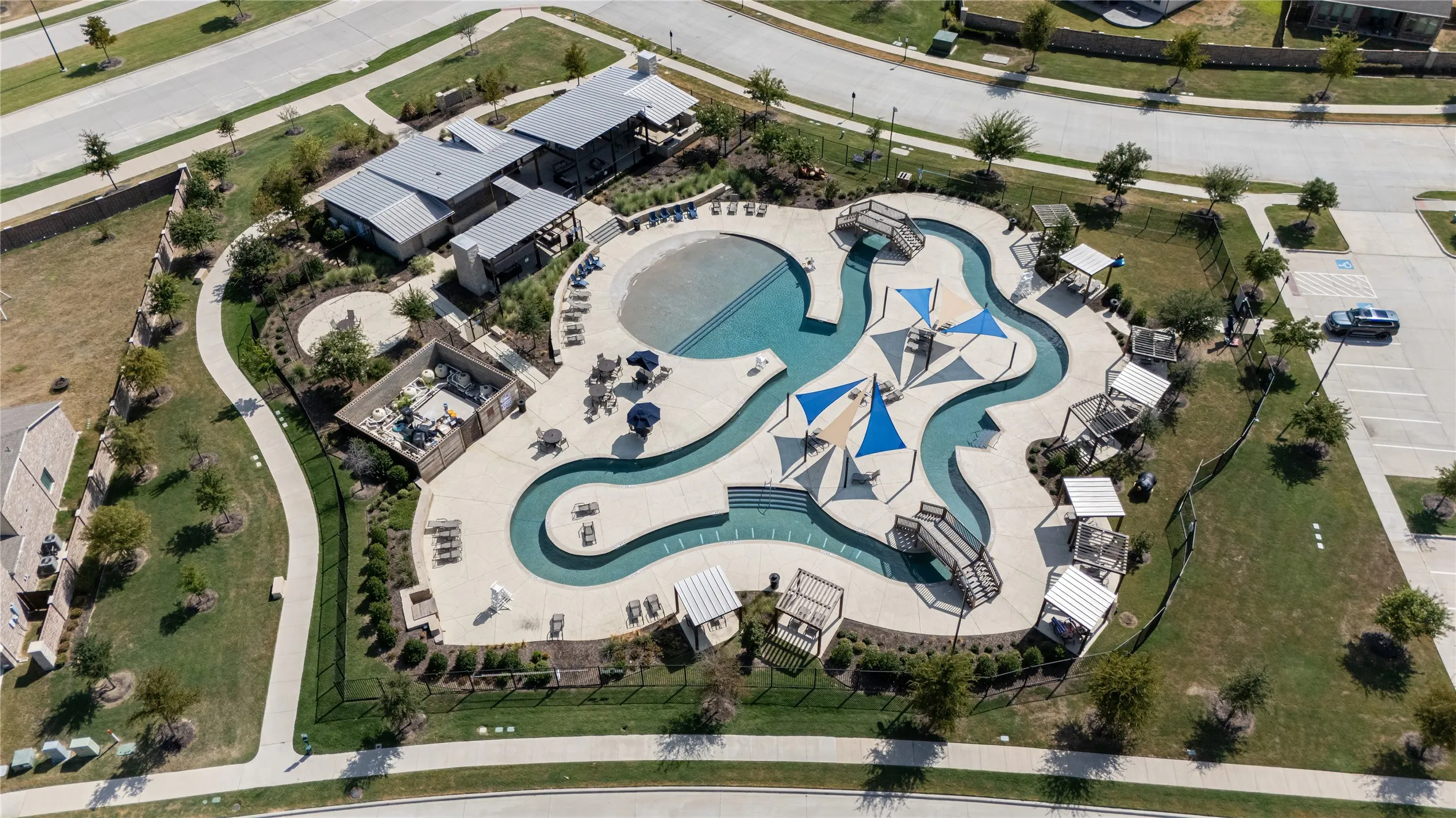 Expansive resort-style pool complex featuring multiple pools, integrated shade structures, bridges, and surrounding lounge areas