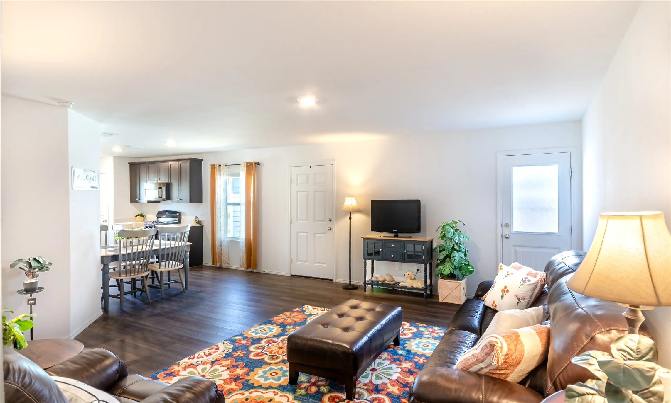 Open-concept living area featuring wood-finish flooring, recessed lighting, and a white paneled door with frosted glass