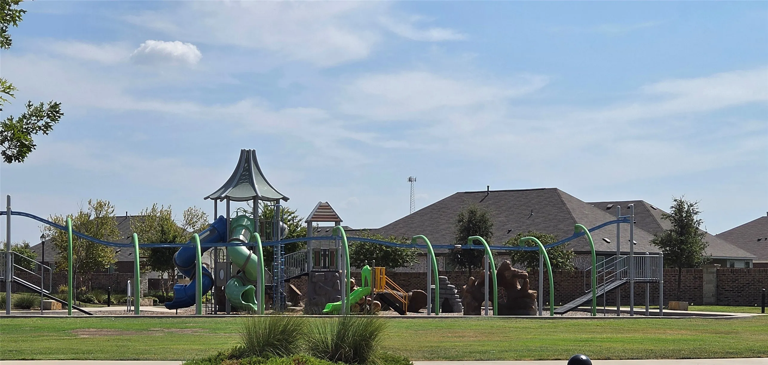 Spacious green space featuring a large playground structure with multiple slides and climbing elements