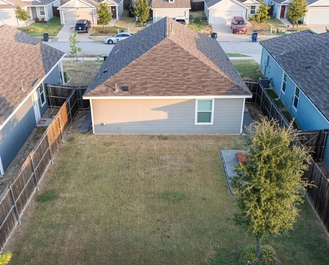 Private backyard featuring a wooden privacy fence, a mature tree, and a paved patio area