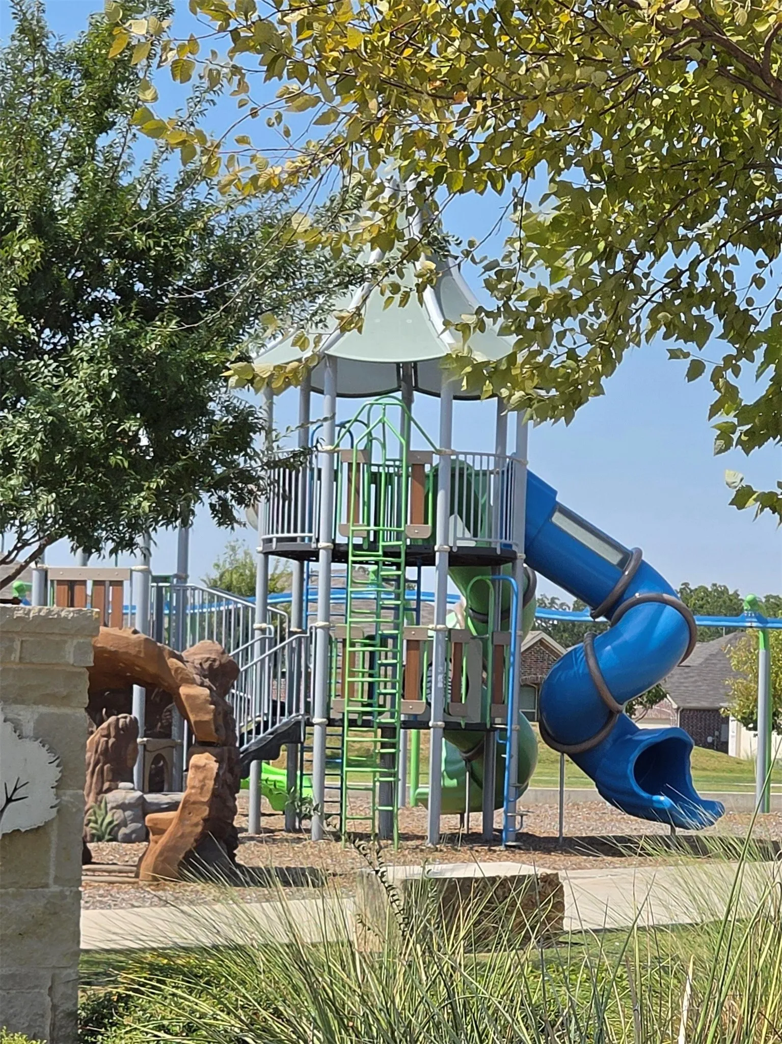 Recreational playground featuring a multi-level play structure, spiral slide, ladder access, and ground-level play elements