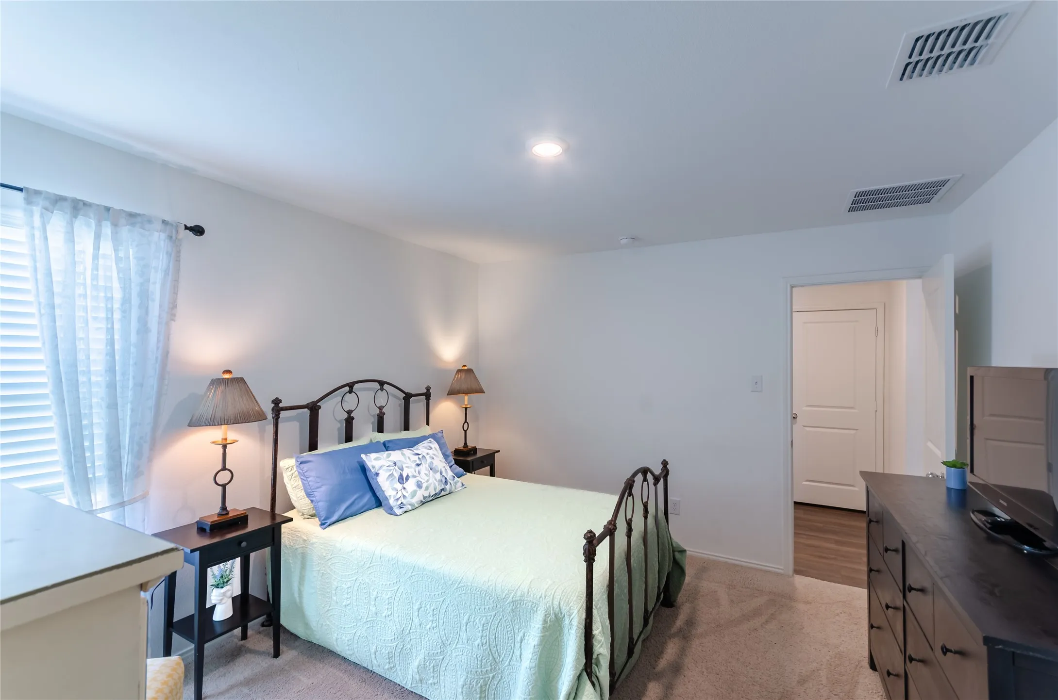 Carpeted flooring, recessed ceiling lighting, textured white walls, a single window with blinds, and a white interior door