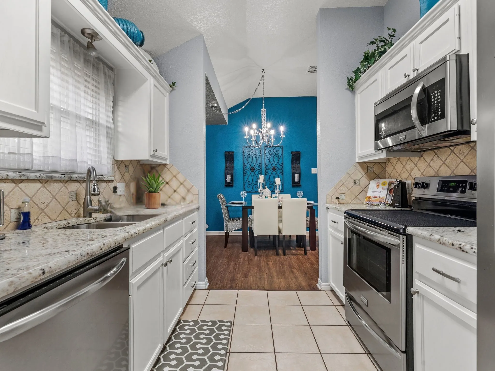White cabinetry with brushed nickel hardware, speckled countertops, stainless steel appliances, and a tiled backsplash