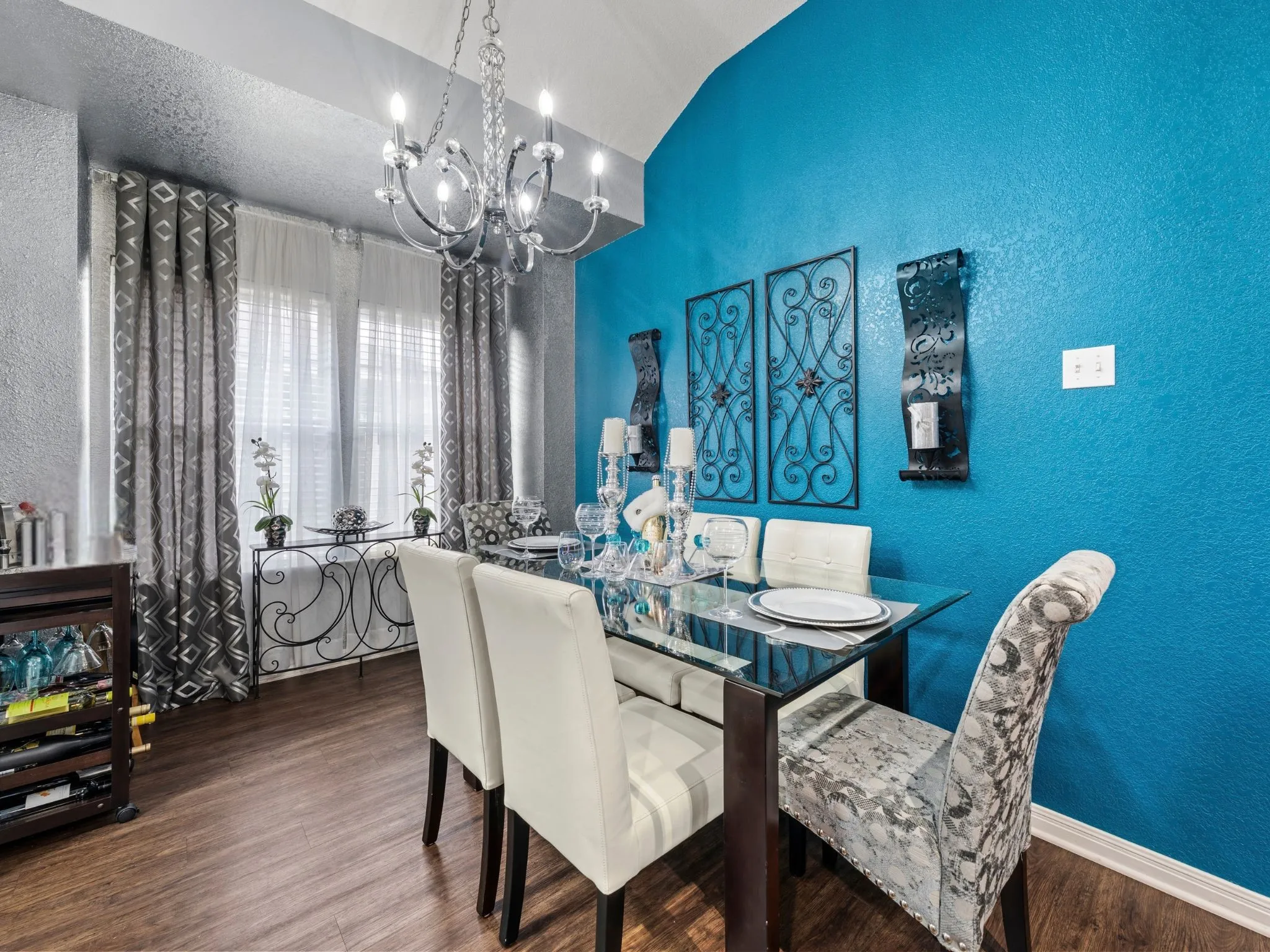 Vaulted ceiling, wood-finish flooring, chandelier, double windows, and a glass-top table