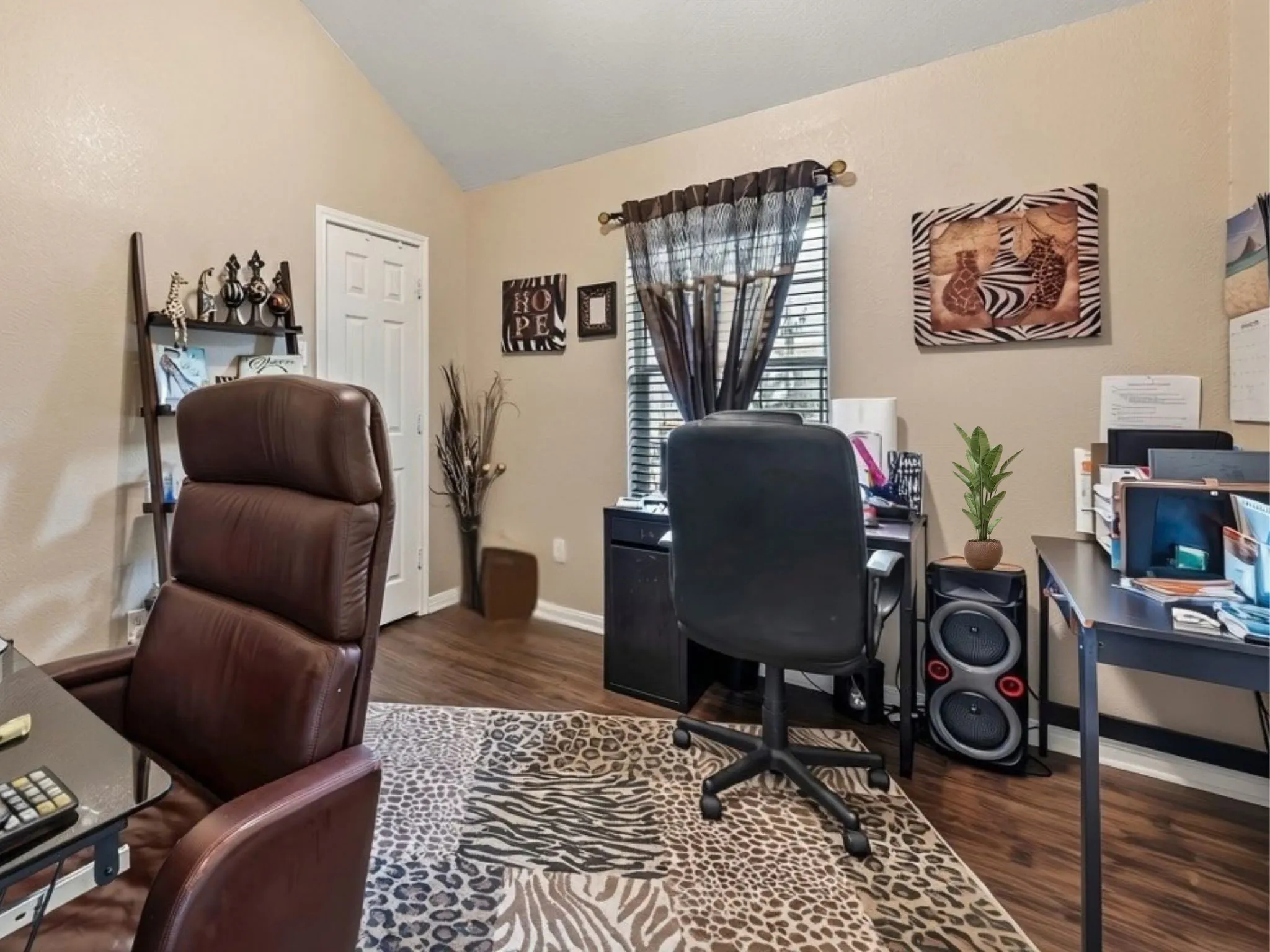Vaulted ceiling with wood-finish flooring, white paneled interior door, and window with blinds