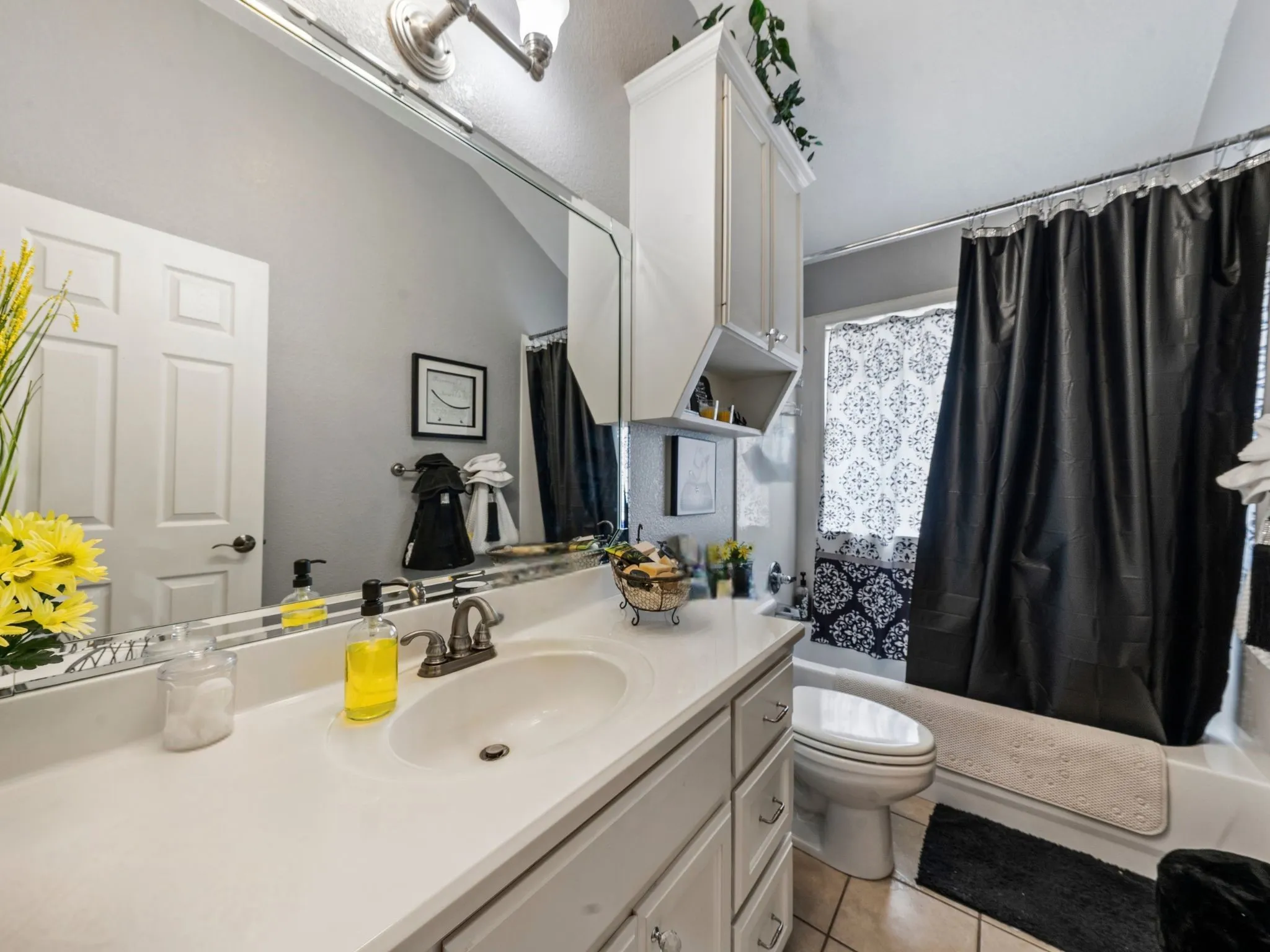 White vanity with integrated sink, brushed nickel faucet, large wall mirror, and overhead lighting