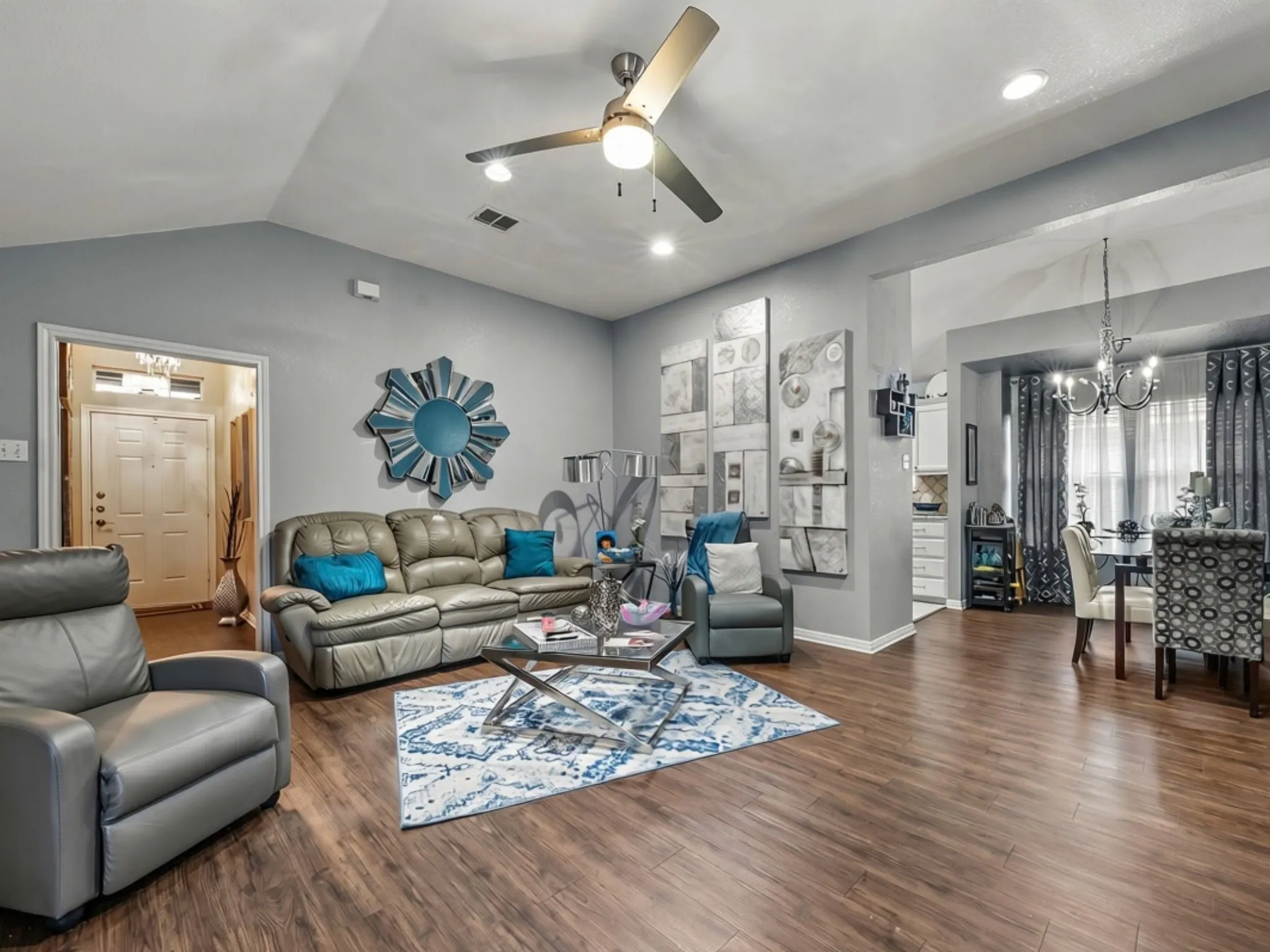 Spacious living area featuring wood-finish flooring, vaulted ceilings, and recessed lighting