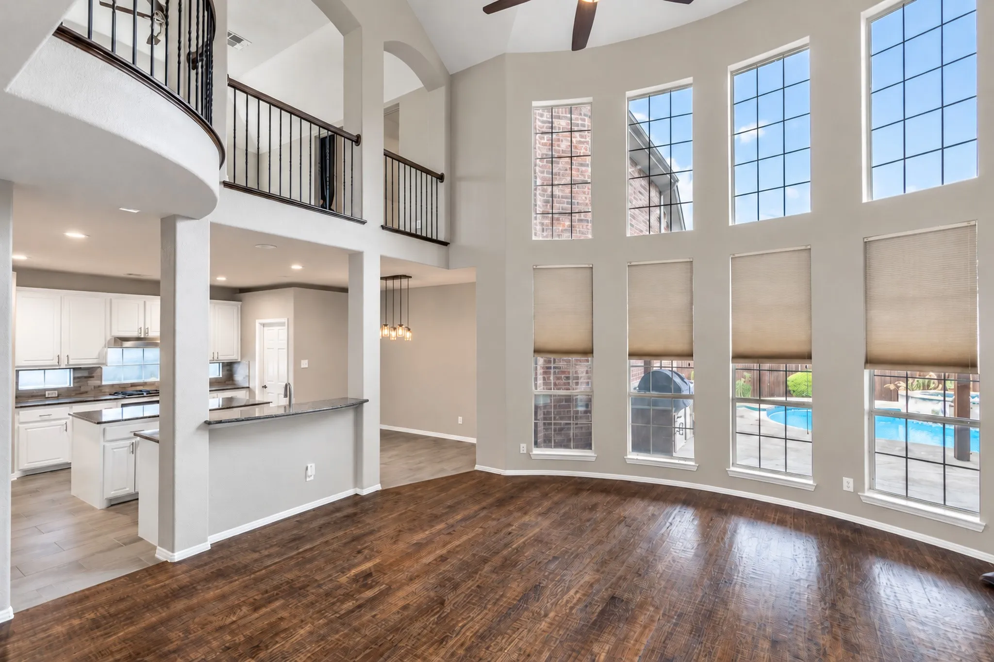 Two-story architectural design with balcony overlook, wood-finish flooring, and a vaulted ceiling