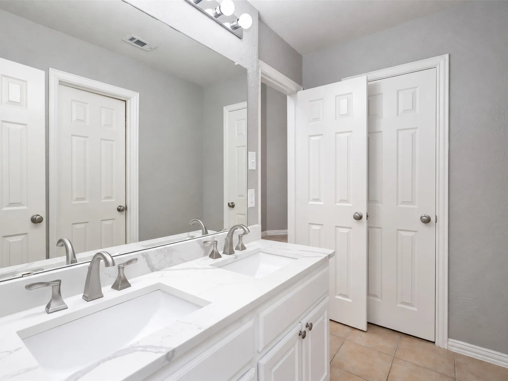 Double vanity with undermount sinks, stone-look countertop, and brushed nickel fixtures