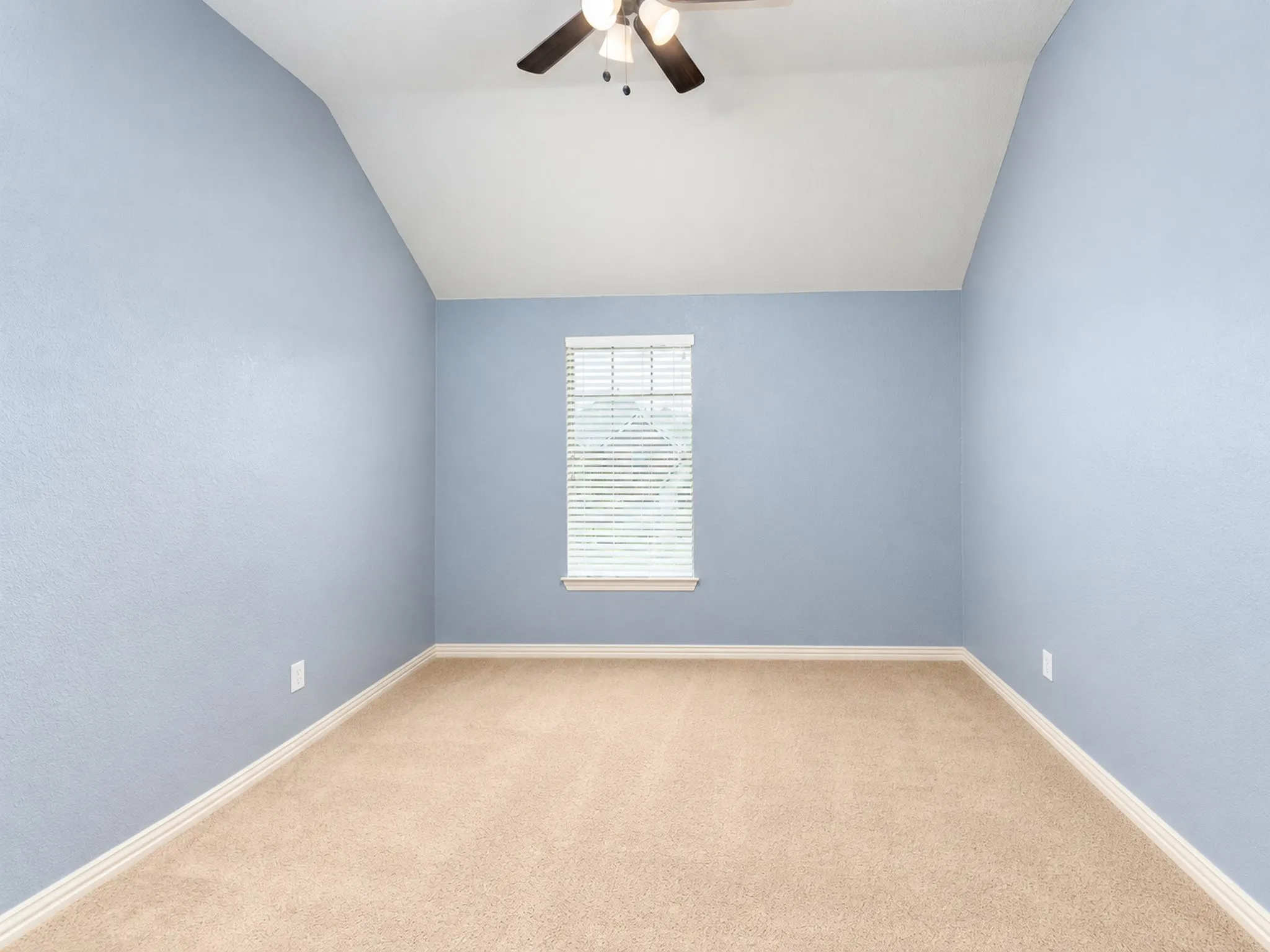 Vaulted ceiling, ceiling fan, single window with blinds, light blue painted walls, and carpet flooring